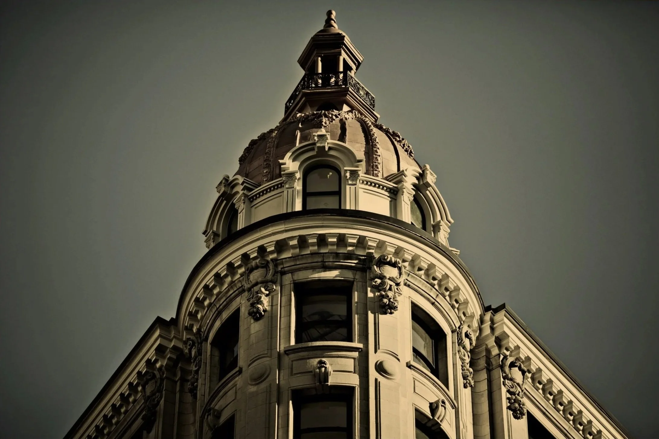 Close-up of a historic building's ornate dome with architectural details, upward view toward the sky.