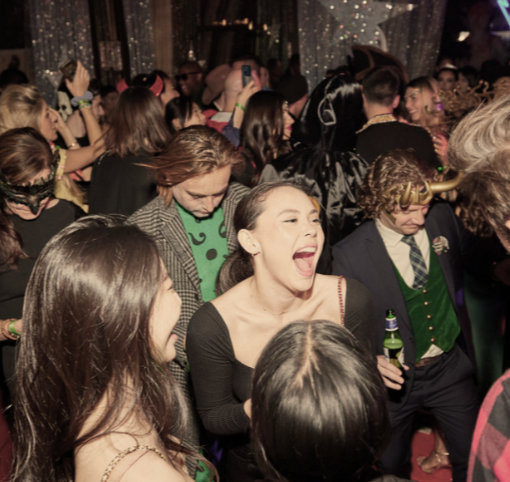 People dancing and enjoying themselves at a lively indoor party with colorful lighting.