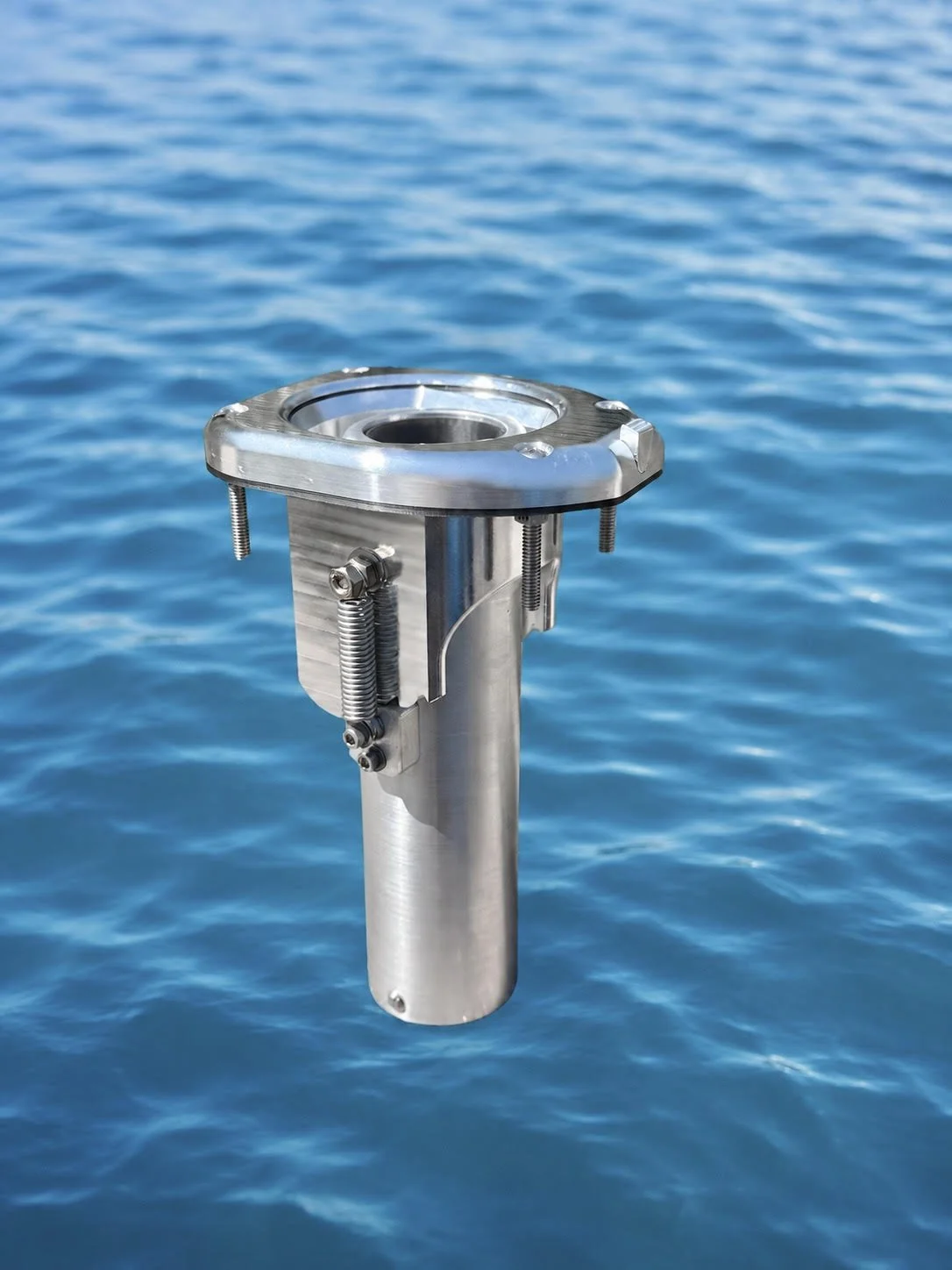 A metallic scientific instrument floating on the ocean surface with blue water in the background.