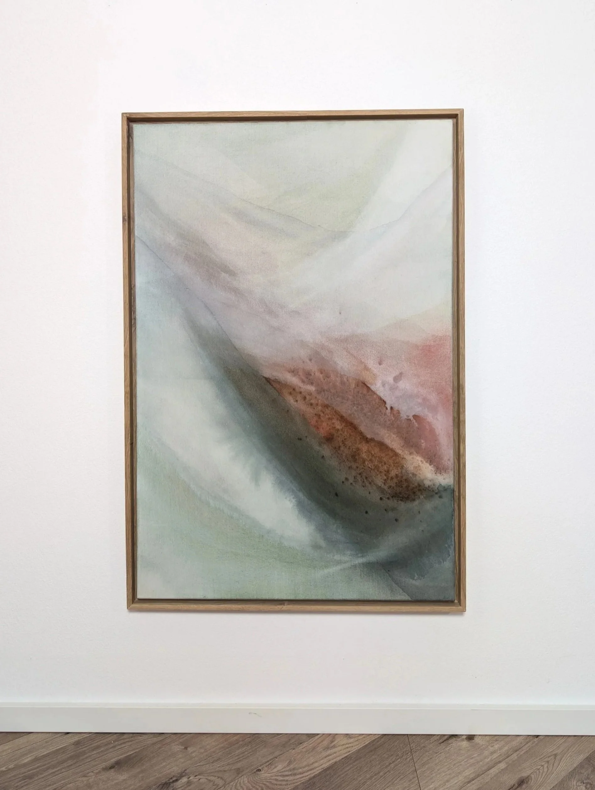 Ein Gemälde mit abstrakten, pastellfarbenen Wellenmustern in einem Holzrahmen, das an einer weißen Wand hängt.