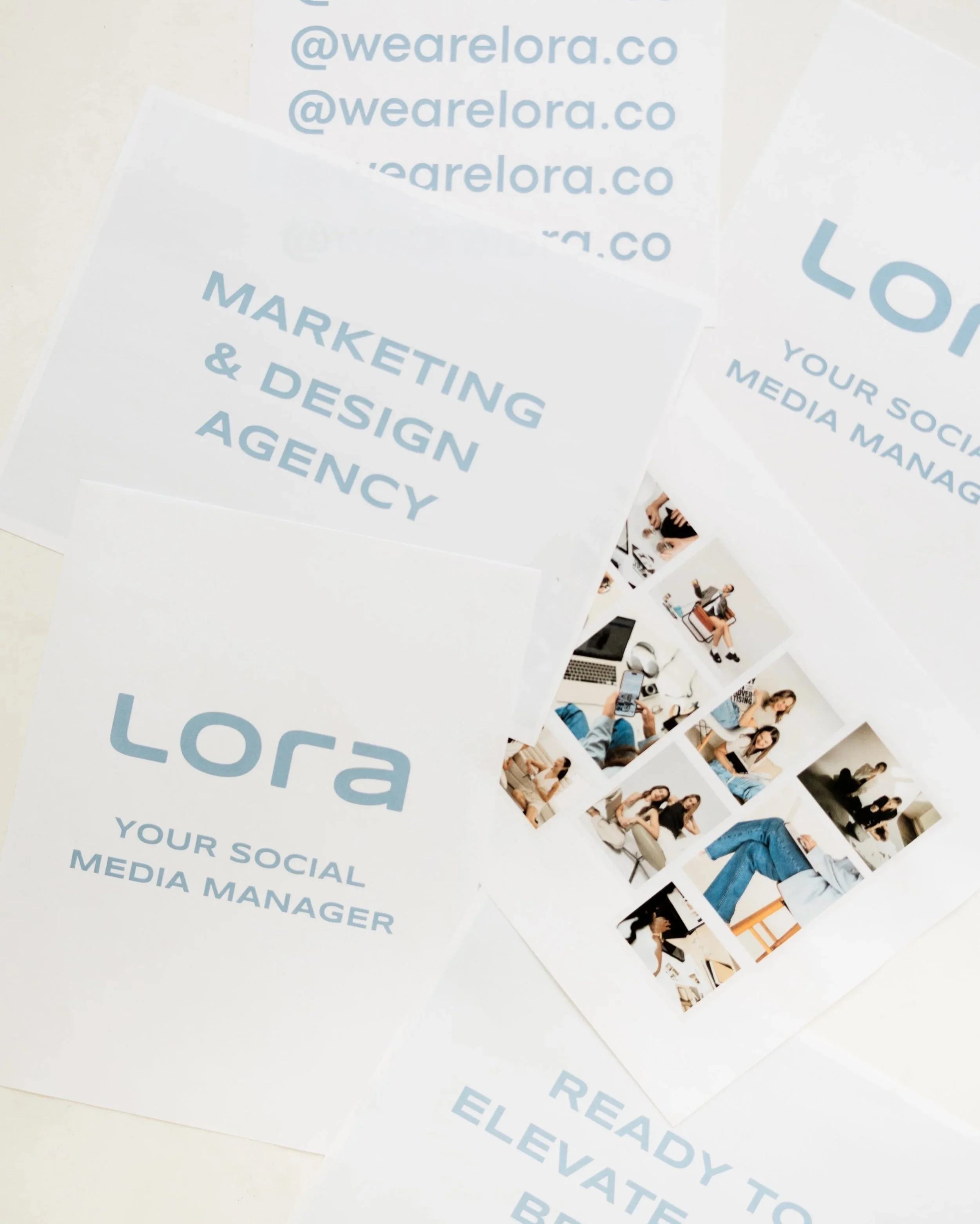 Printouts with text related to marketing, social media management, and branding, including the URL '@wearelora.co', and images of people working on electronic devices and collaborating.