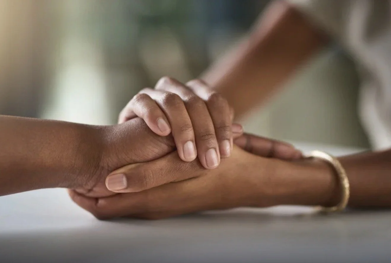 Close-up of two hands holding each other, symbolizing support and connection.