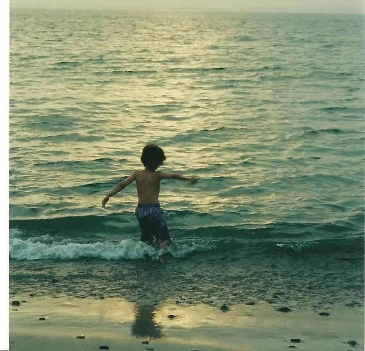 Child playing in the ocean at sunset.