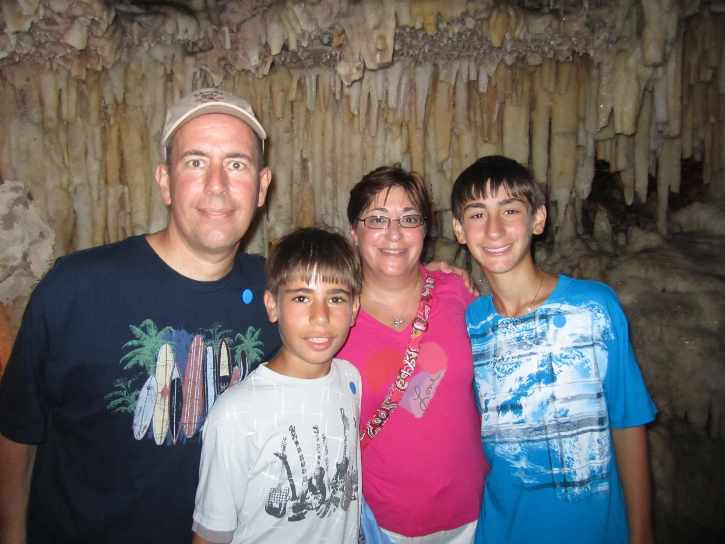 Family of five posing inside a cave with stalactites and stalagmites