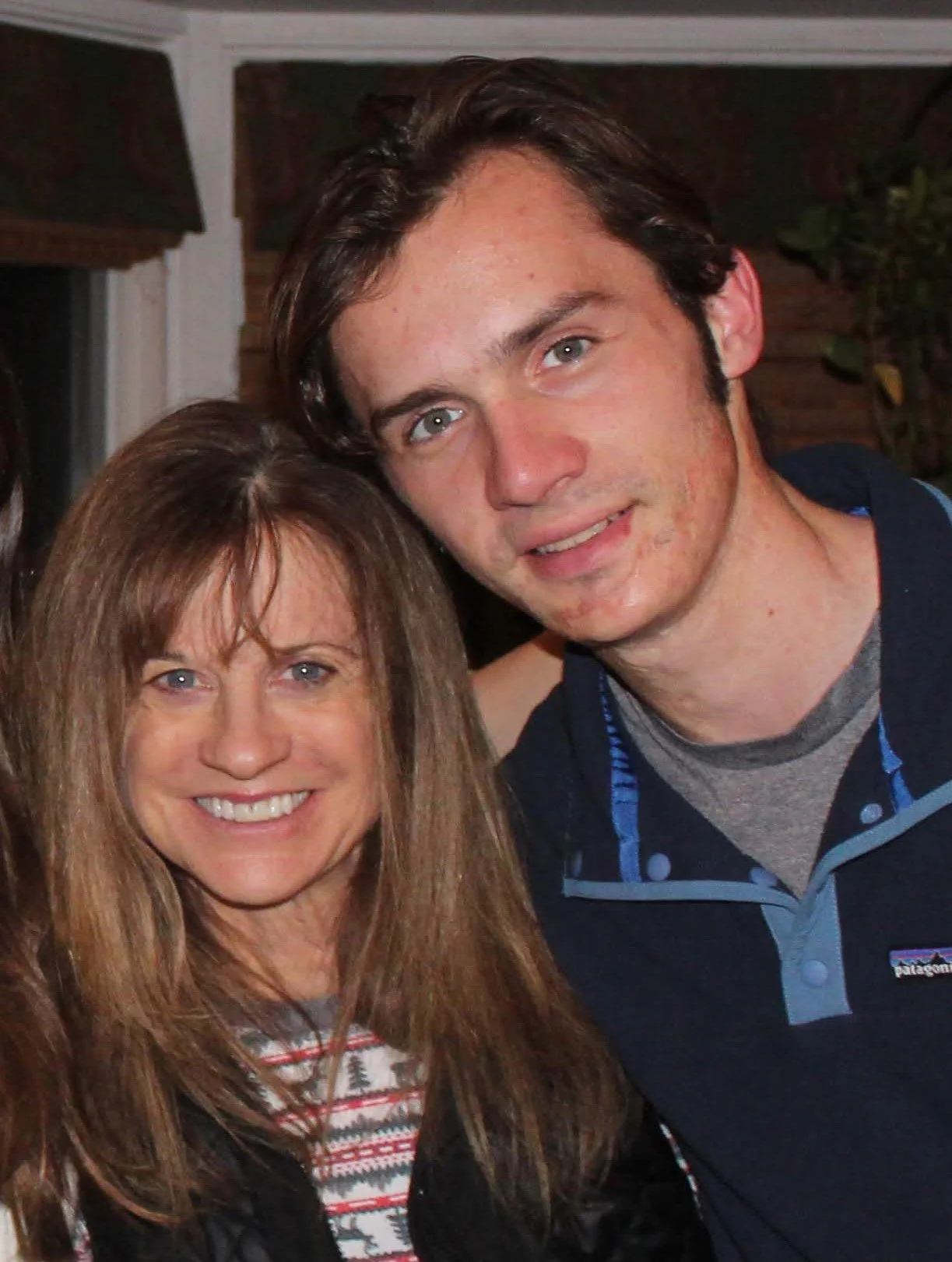 A woman with long, reddish-brown hair and a man with short, dark hair smiling and posing together in an indoor setting.