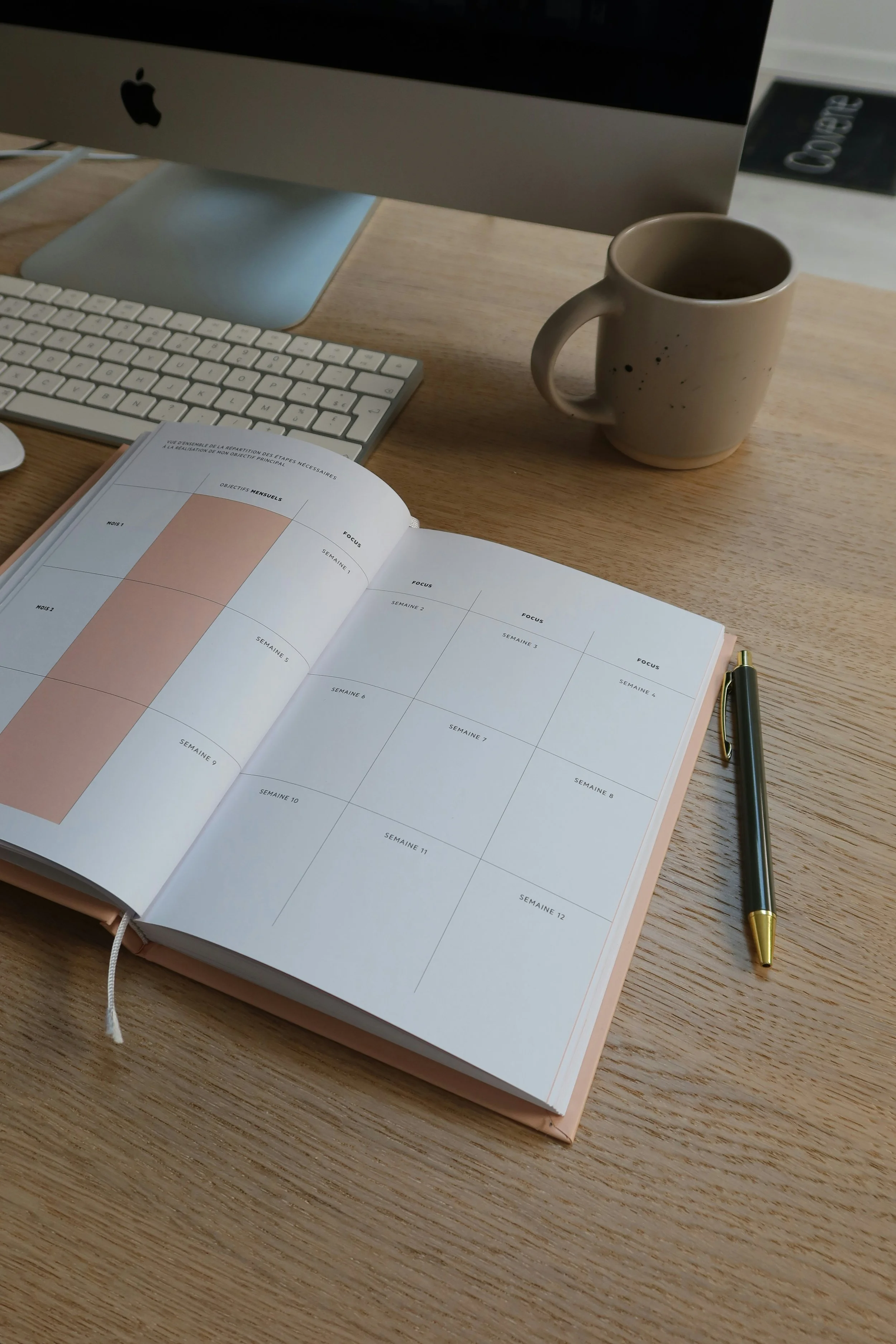 A desk with an iMac computer and Otiti's agenda.