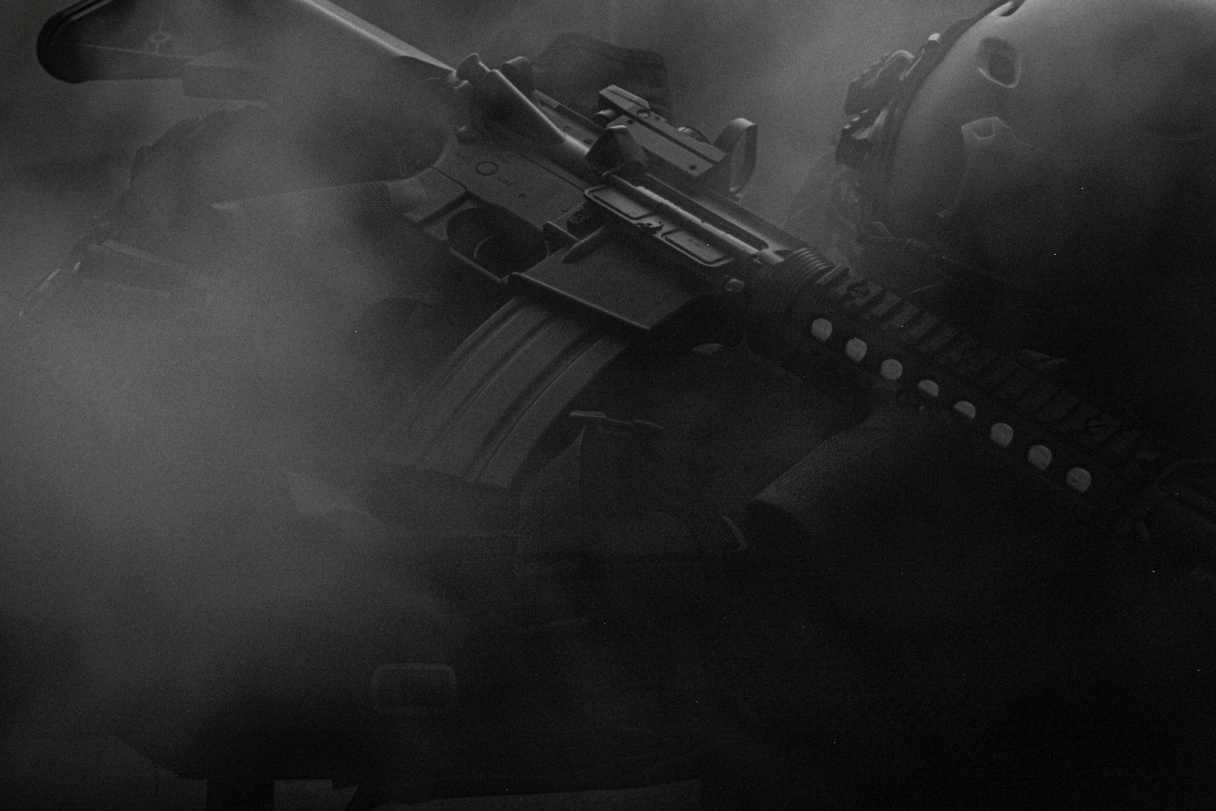 A firearm, specifically a semi-automatic handgun, is placed on a surface in a dark environment. The gun is partially in focus, with details like the slide, trigger, and grip visible.