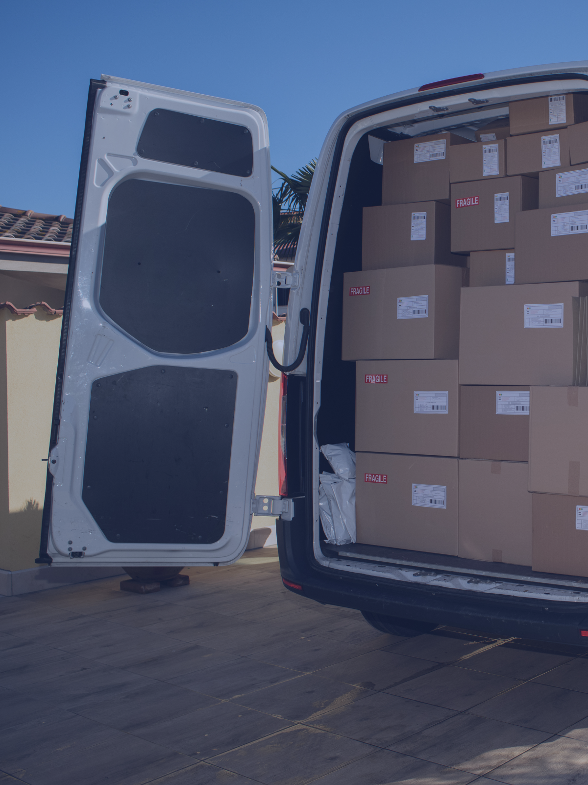 Open cargo van filled with boxes labeled fragile, parked outdoors on a sunny day with a clear blue sky.