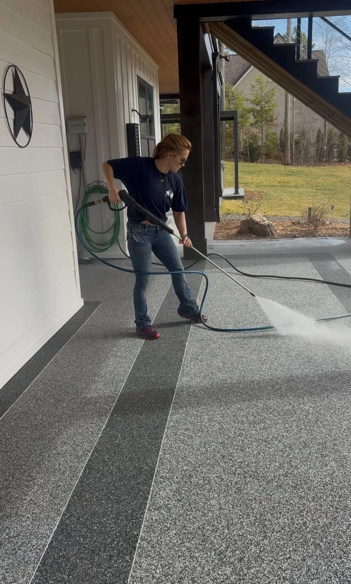 Woman cleaning outdoor patio floor with a power washer.