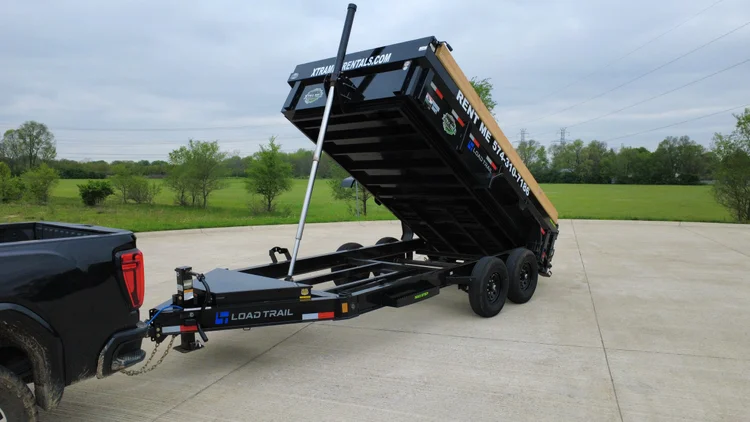 Xtra Mile dump trailer with its bed raised.