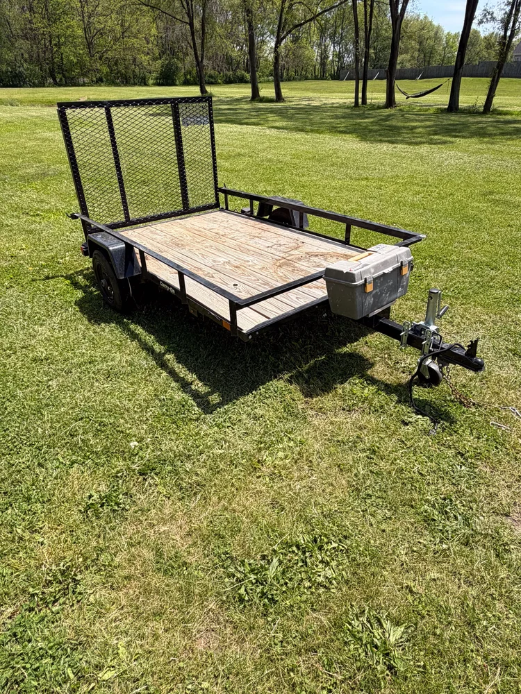 Open utility trailer with a wood deck and rear loading ramp.