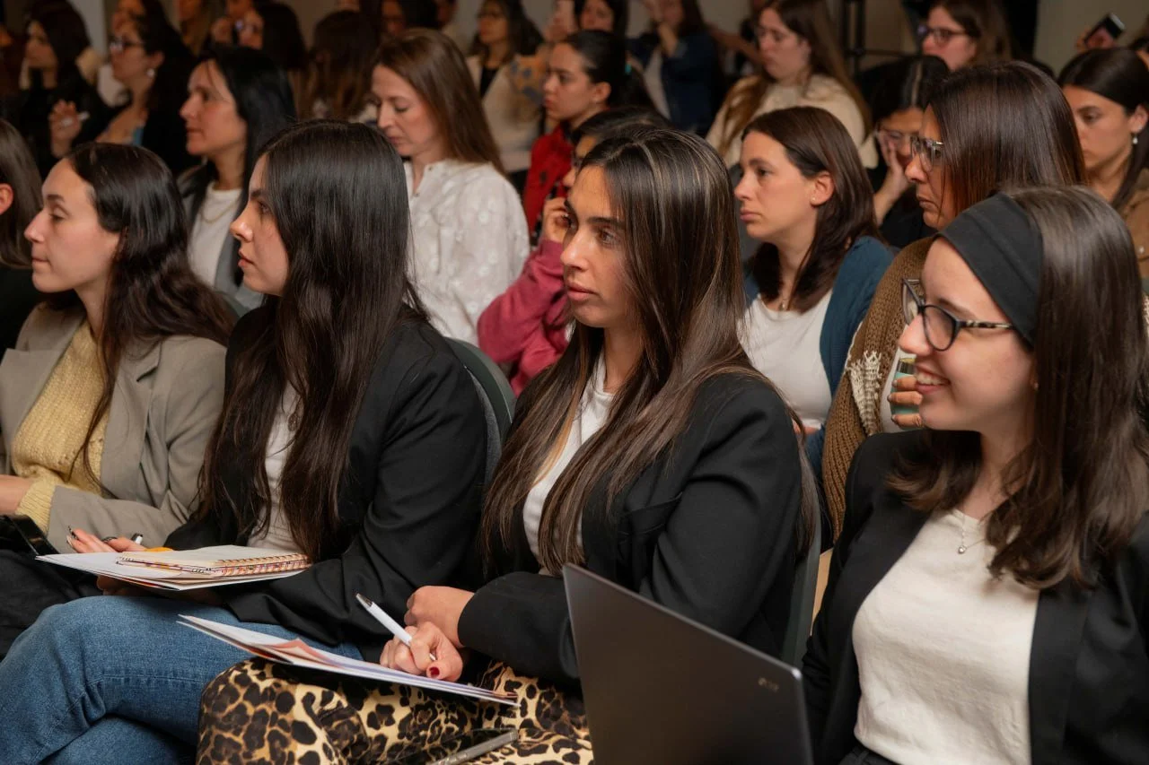 Varias mujeres sentadas en un auditorio, participando en una conferencia o seminario.