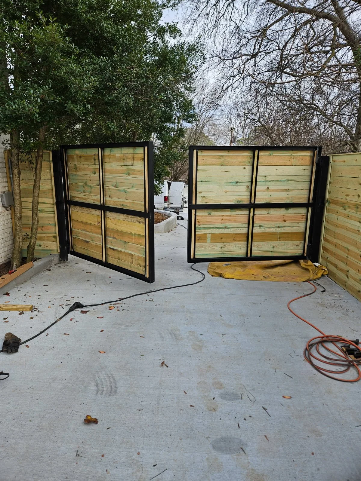 Custom ornamental steel and wood privacy driveway gate. Features a precision-engineered heavy-duty steel frame integrated with horizontal wood slats, custom-fabricated to deliver high-end security and a modern architectural look.
