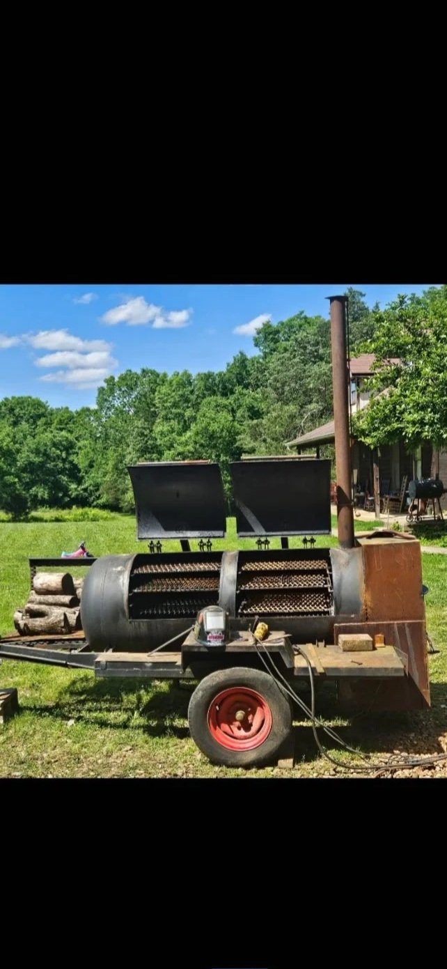 Custom mobile commercial-grade offset smoker with an integrated firewood wood box, engineered for pitmasters and backyard catering events.