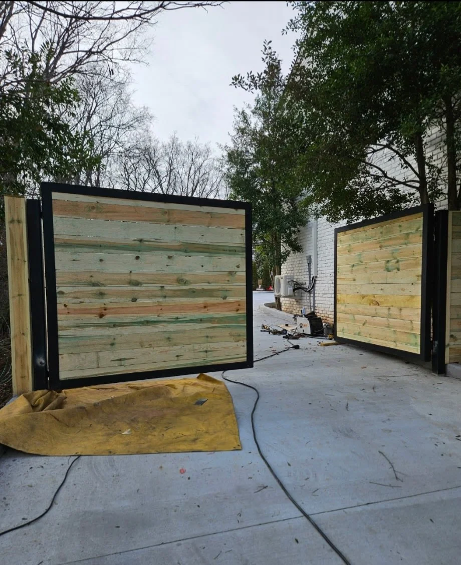 Heavy-duty ornamental steel and wood dual-swing driveway gate. Custom-fabricated with a durable steel framework and privacy wood panels, engineered with robust gate hardware for flawless, long-lasting operational performance.