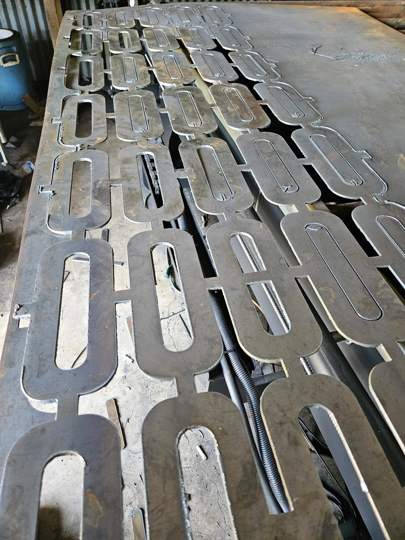 Precision CNC plasma-cut structural components, nested and cut from a single heavy-duty steel plate. This showcases the exact edge quality and tight tolerances achieved during the raw fabrication phase before assembly and finishing.