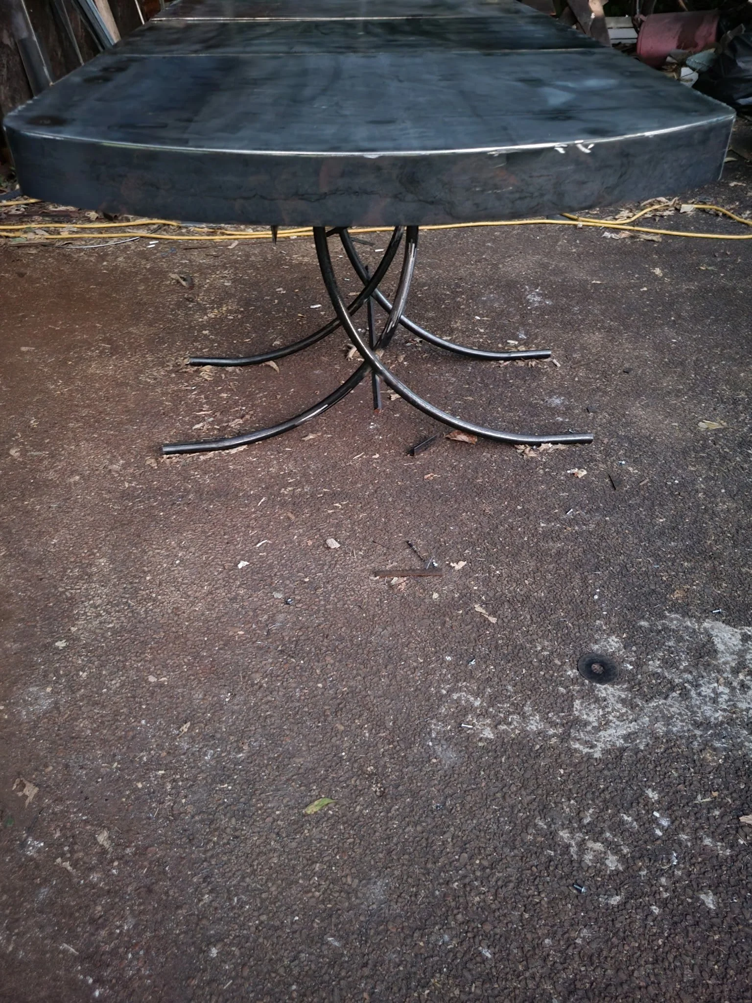 Custom round industrial dining table. Features a bespoke, artistically hand-forged steel base with elegant curved legs, bringing a unique architectural statement piece to any modern dining room.