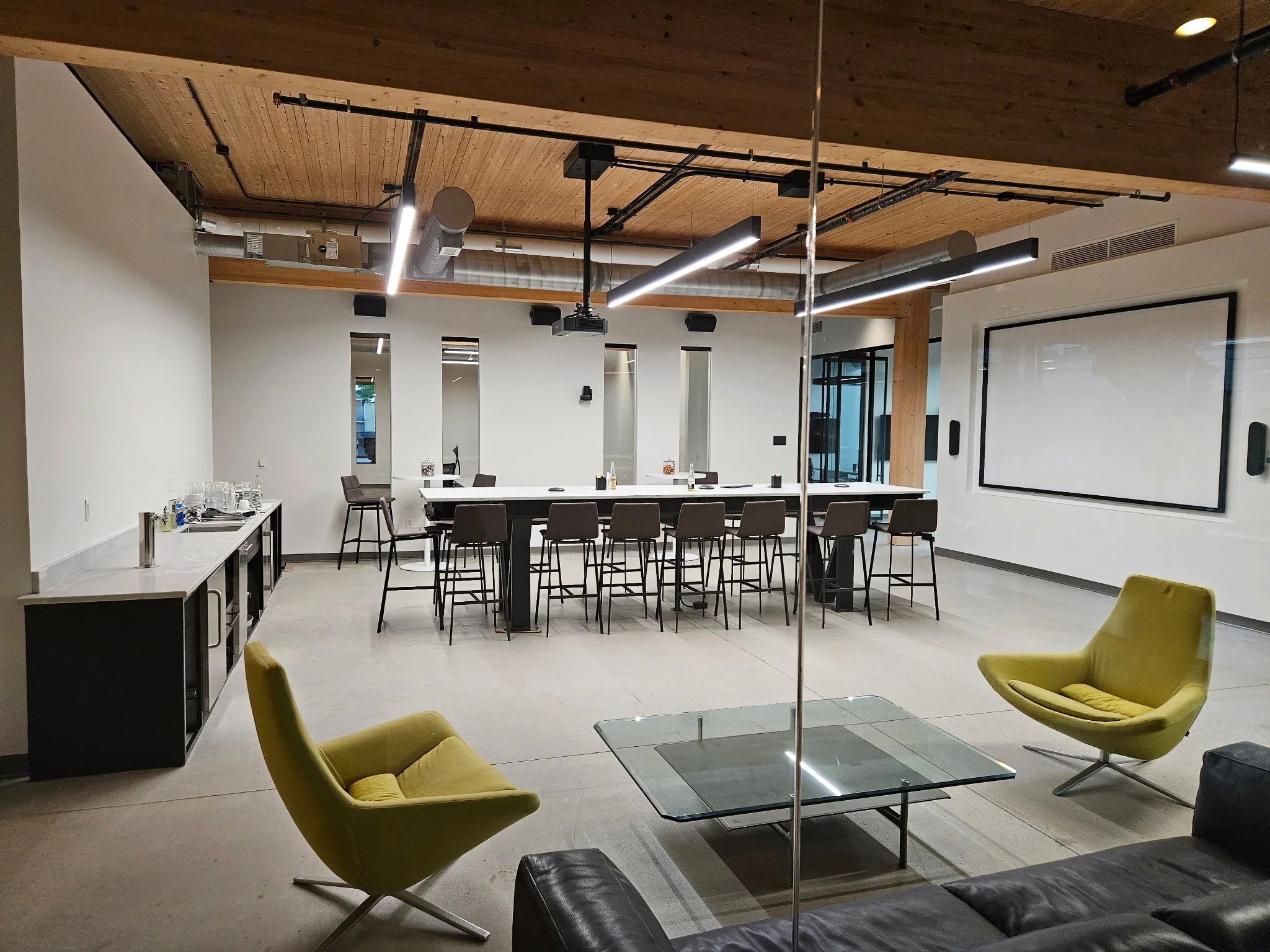 Custom commercial modern industrial interior build. Highlighting a massive, heavy-duty communal conference table engineered to bring sleek architectural design and durable functionality to corporate lounges and modern workspaces.