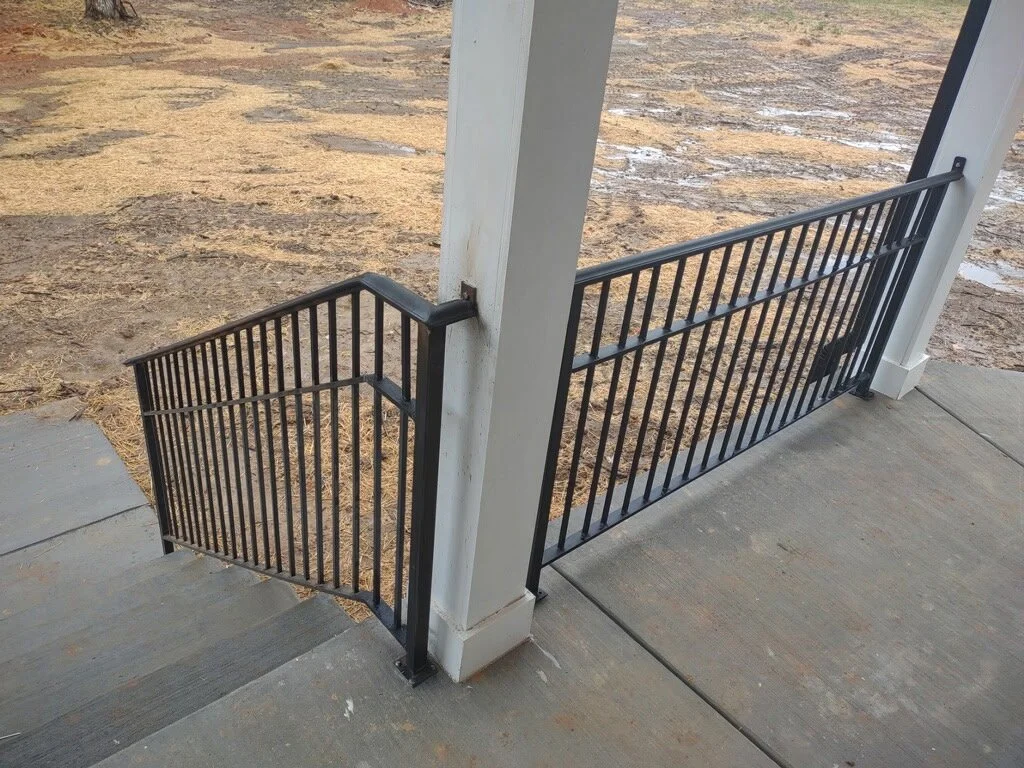 Custom exterior residential steel porch railing. Features a durable, low-profile horizontal bar design mounted directly to structural columns, providing a clean modern look with superior stability.
