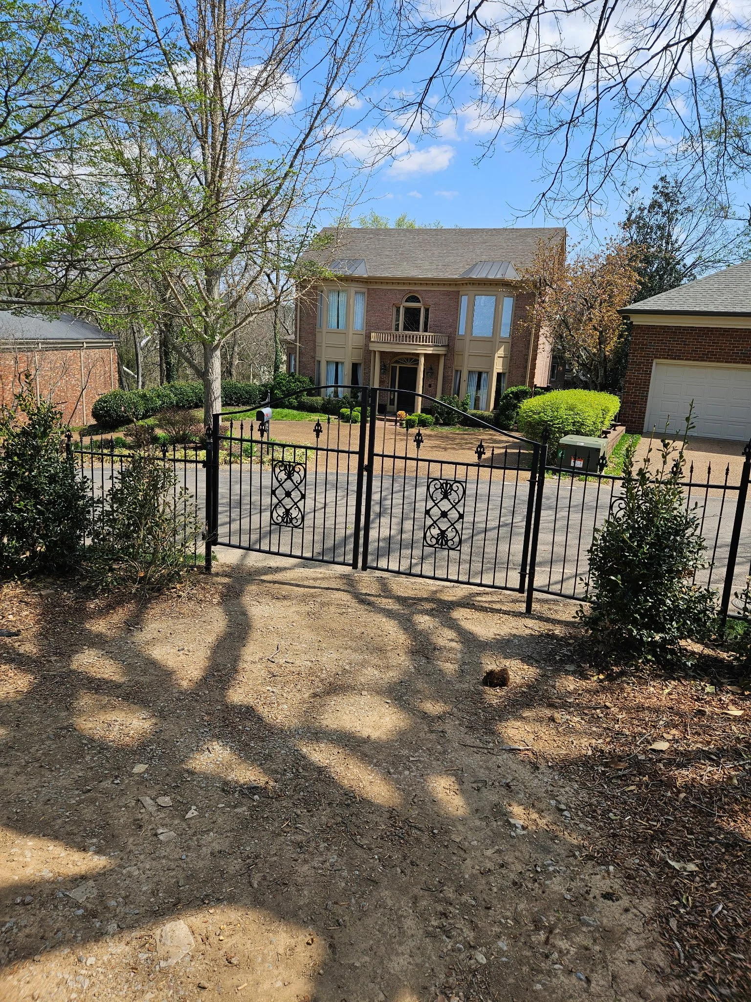 Custom ornamental steel driveway gate. Features a classic spear-top design with integrated decorative scrolls and heavy-duty structural hinges, precision-engineered for long-term durability and automated access systems.