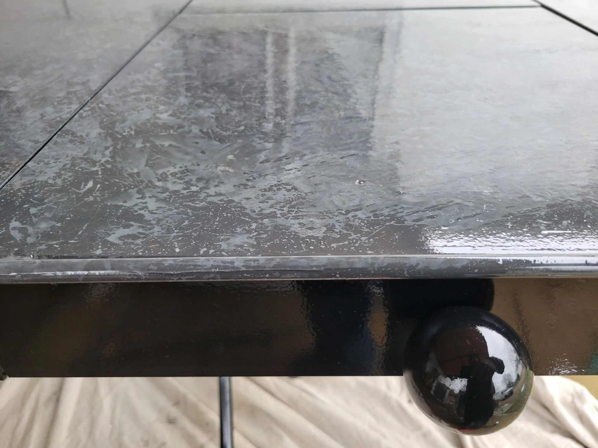 High-end modern industrial finish detail. Close-up showcasing a flawless, premium polished tabletop surface perfectly inset into a custom-welded structural steel frame with architectural accent detailing.