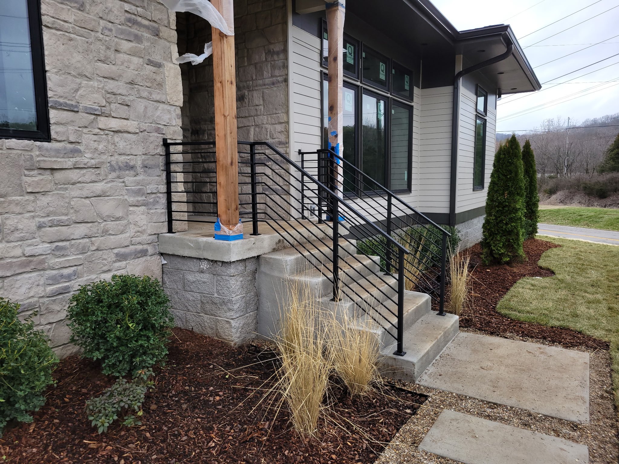 Custom residential side-mount steel handrail. Engineered with clean vertical pickets to perfectly complement modern stone masonry while providing robust, secure entry safety.
