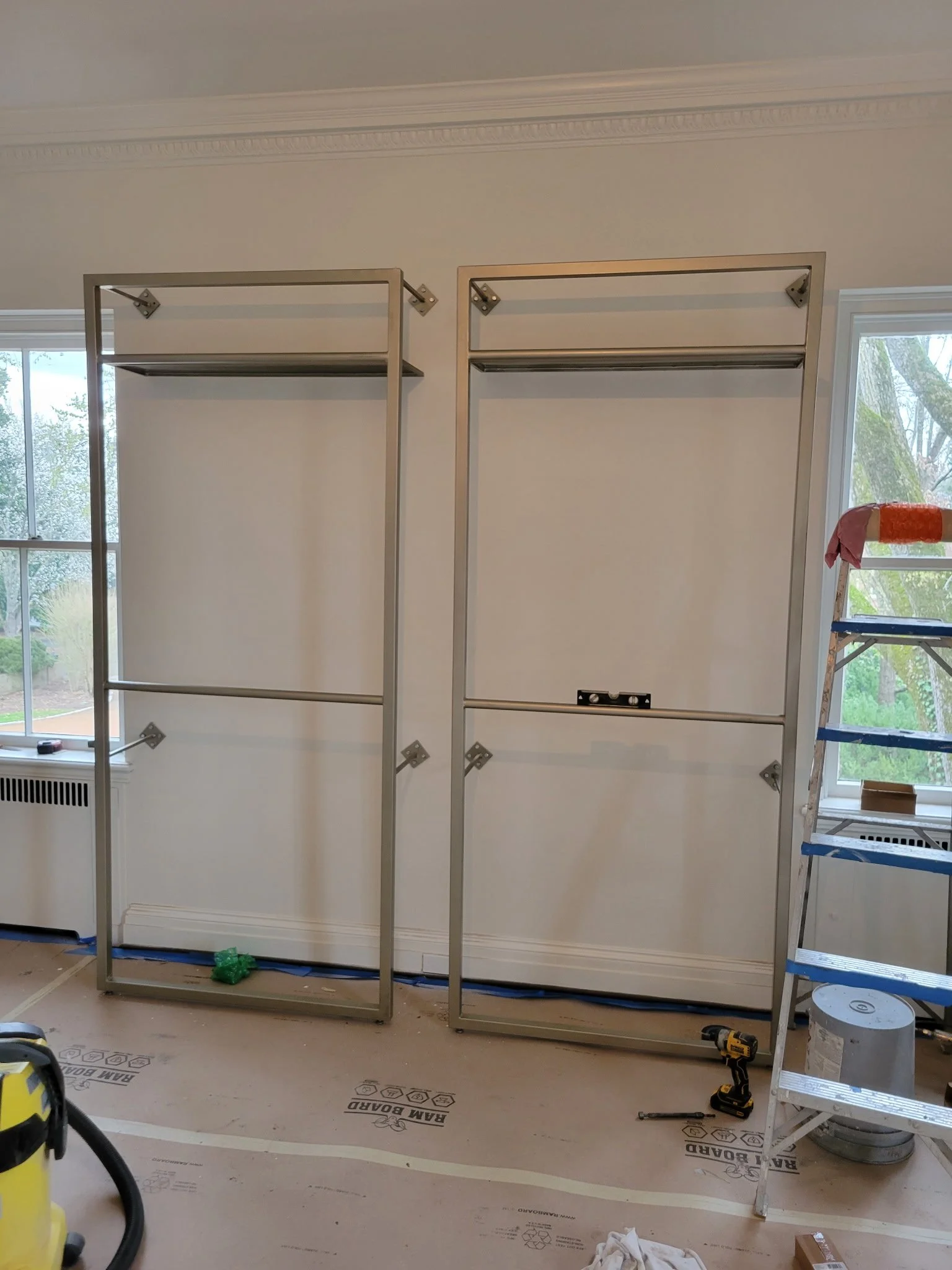 Custom freestanding double-tiered industrial garment racks under construction. Heavy-duty steel frames precision-welded for maximum stability, designed to handle large-scale clothing displays for commercial retail boutiques.