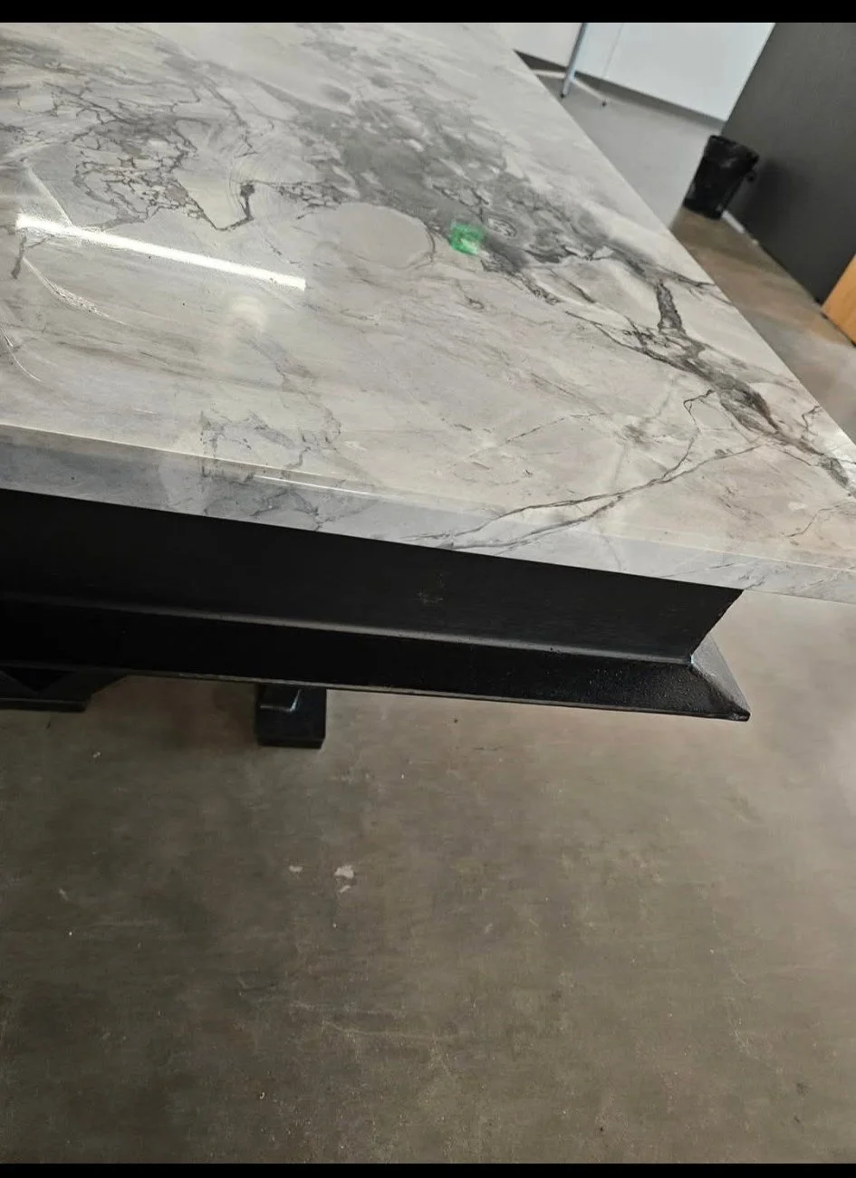 Close-up structural detail of the custom industrial utility counter. Highlighting the heavy-gauge steel framework and precision-welded mounting tabs engineered to securely support the premium solid-surface countertop. Built for uncompromising strengt