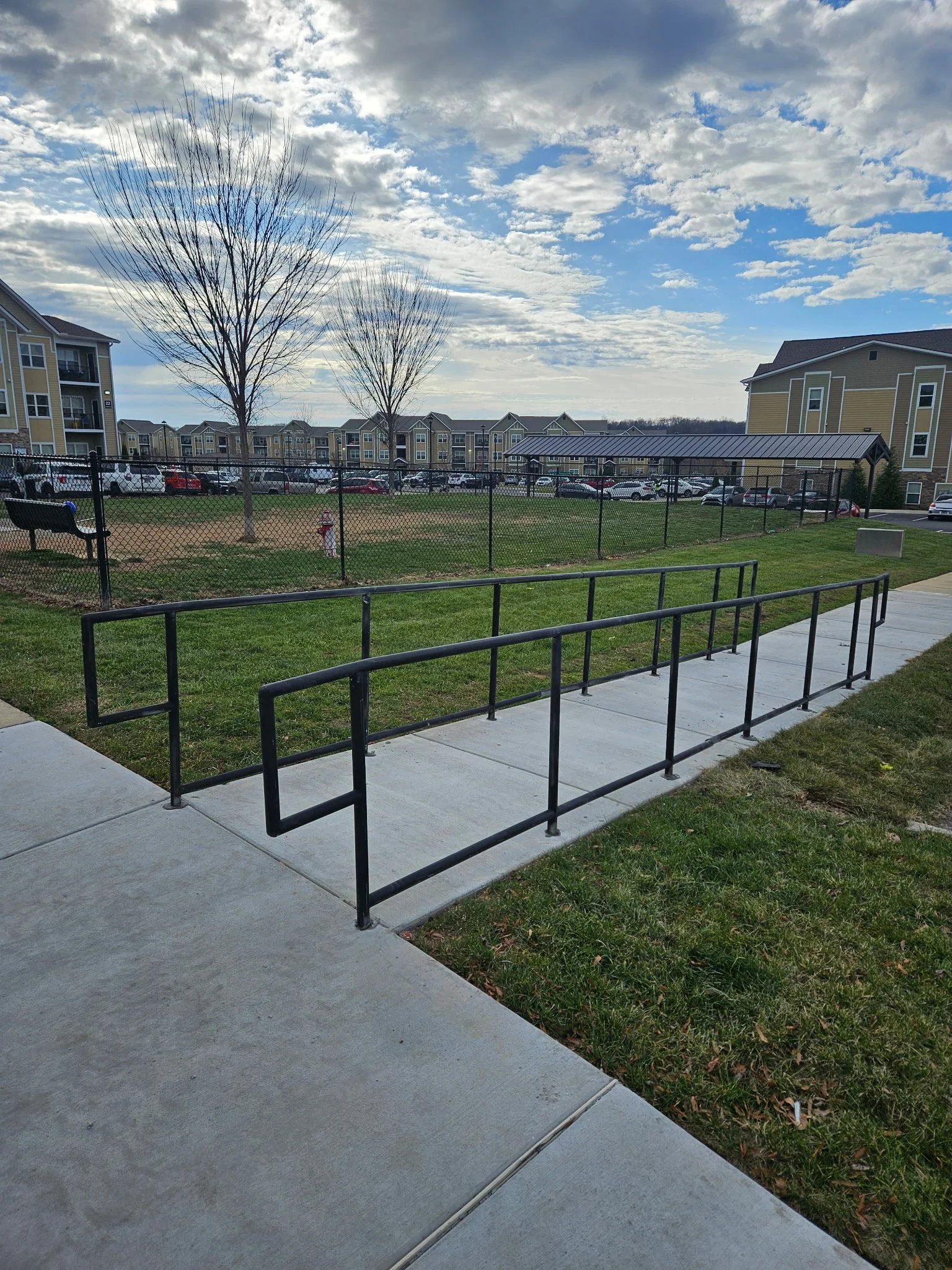 Custom outdoor steel ramp handrail system. Built with commercial-grade structural steel and a durable weather-resistant black finish, precision-aligned to provide continuous safety along concrete walkways.