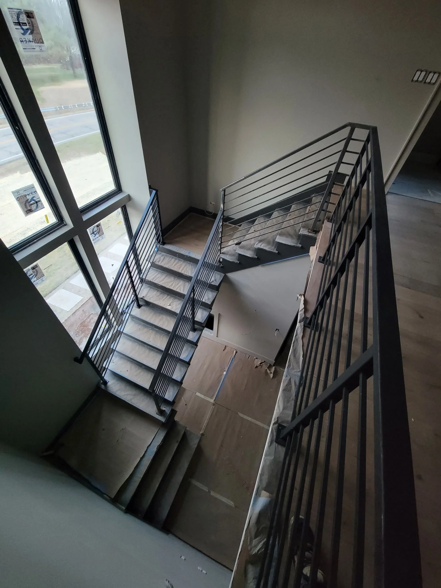 Custom multi-story interior steel staircase railing. Features a continuous horizontal handrail design with precision-welded corners and a sleek, industrial aesthetic that maximizes structural safety and visibility.