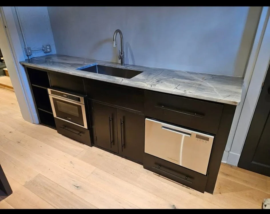 Custom modern industrial kitchenette and utility counter. Features a precision-welded, heavy-gauge steel framework engineered to seamlessly integrate a built-in sink and stainless appliances. Finished with sleek architectural steel cabinetry and a pr