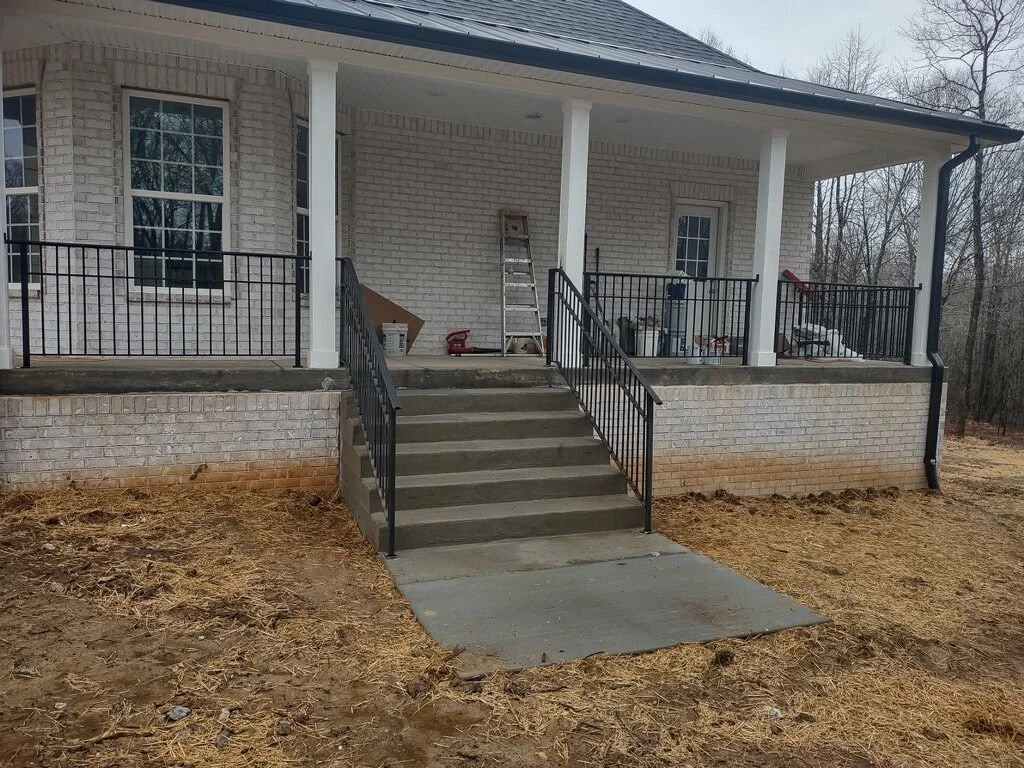 Custom residential front porch handrail and step railing system. Features clean vertical pickets and a matching handrail design that perfectly accents the home's entryway while providing secure, sturdy support.