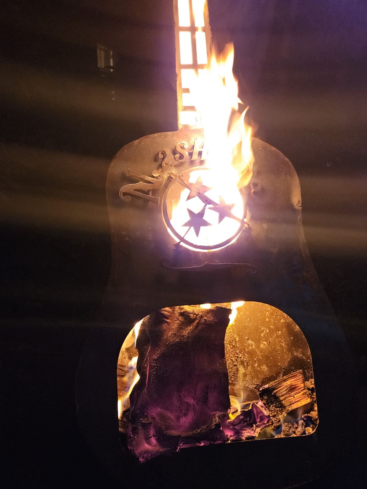 Custom CNC plasma-cut steel fire pit featuring a roaring fire that illuminates a precision-cut custom logo. Built from thick, warp-resistant steel plate.