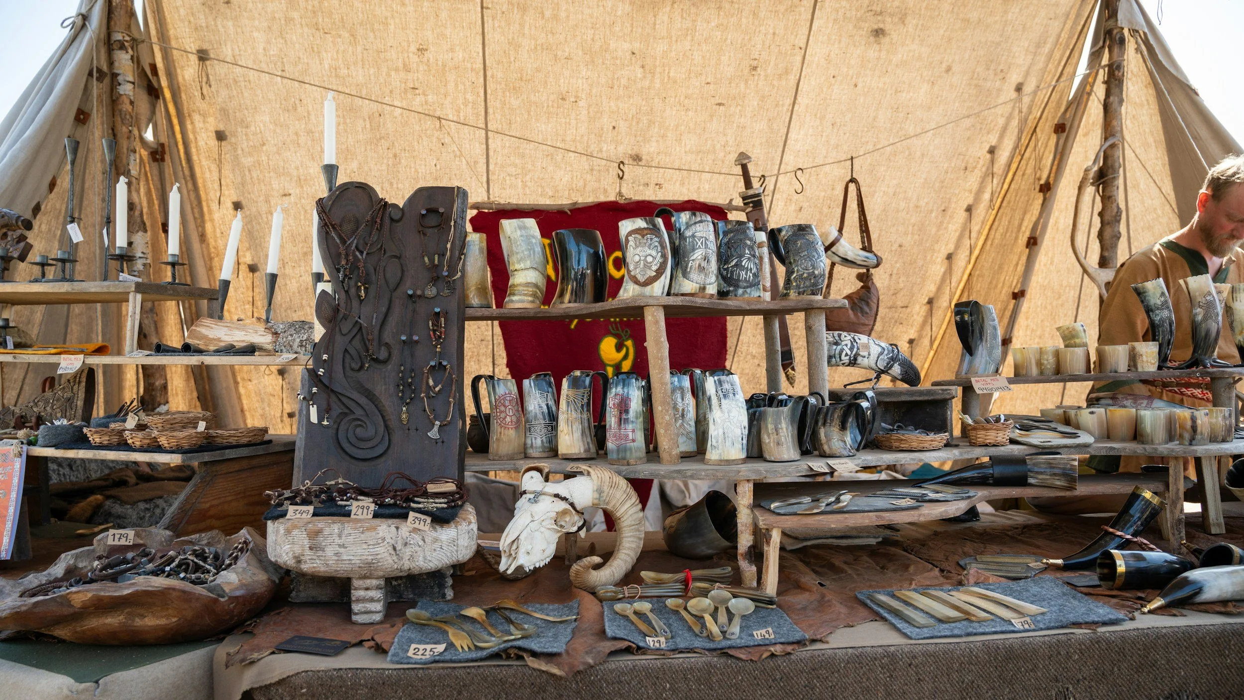 A display of carved tusks, jewelry, and decorative objects on a wooden market stall under a tent.