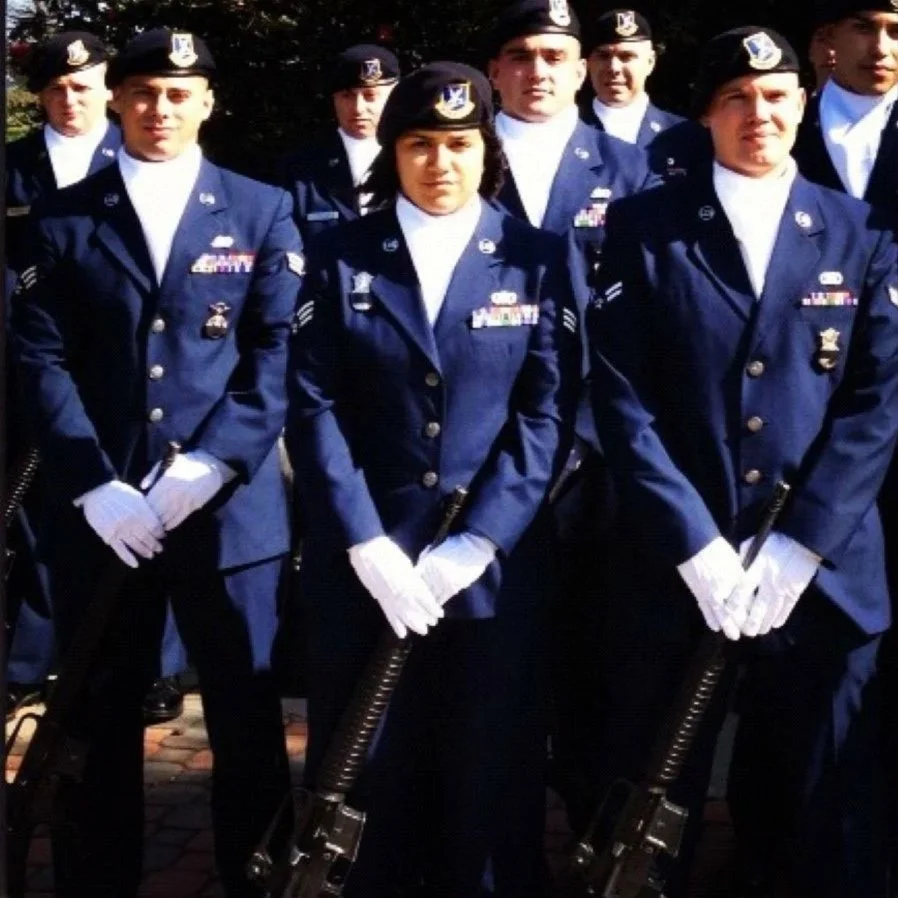 A group of United States Air Force officers in dress uniform standing outdoors, holding rifles, with some wearing white gloves, during a formal ceremony or parade.