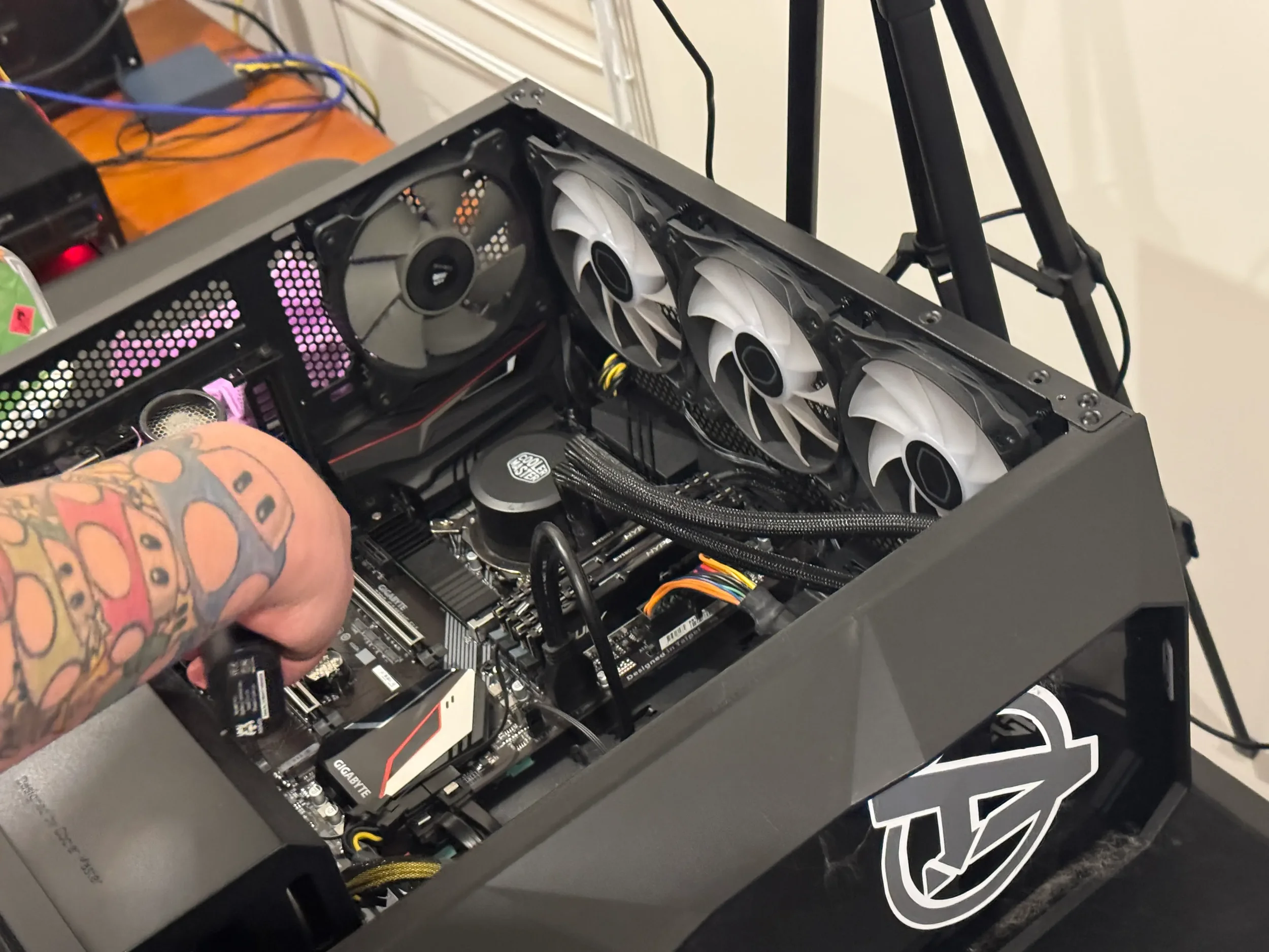 Close-up view of a computer mining rig with multiple cooling fans, a graphics card, and various internal components inside a black case.
