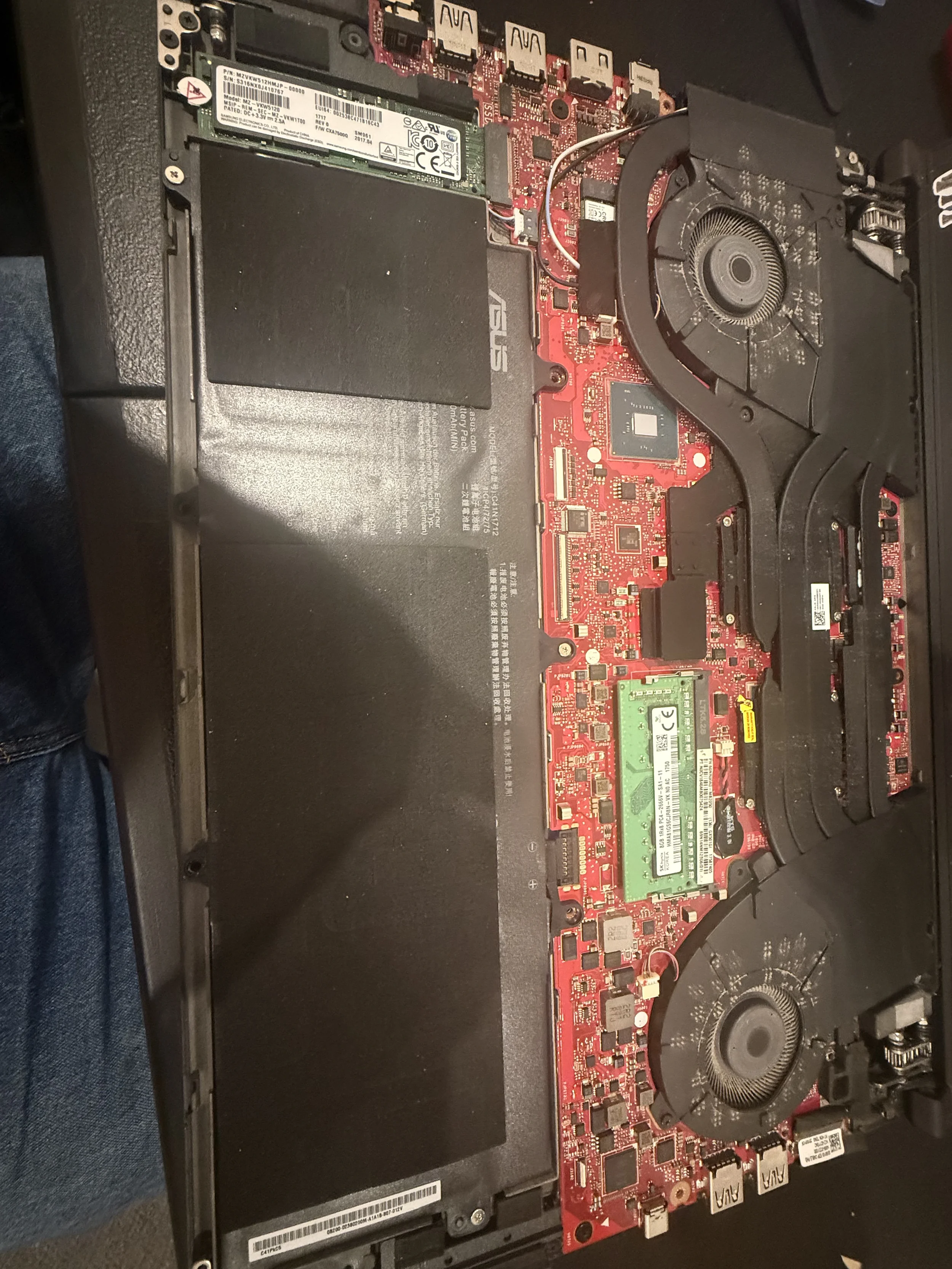 Inside view of a laptop showing a red circuit board with various electronic components, cooling fans, and memory modules.