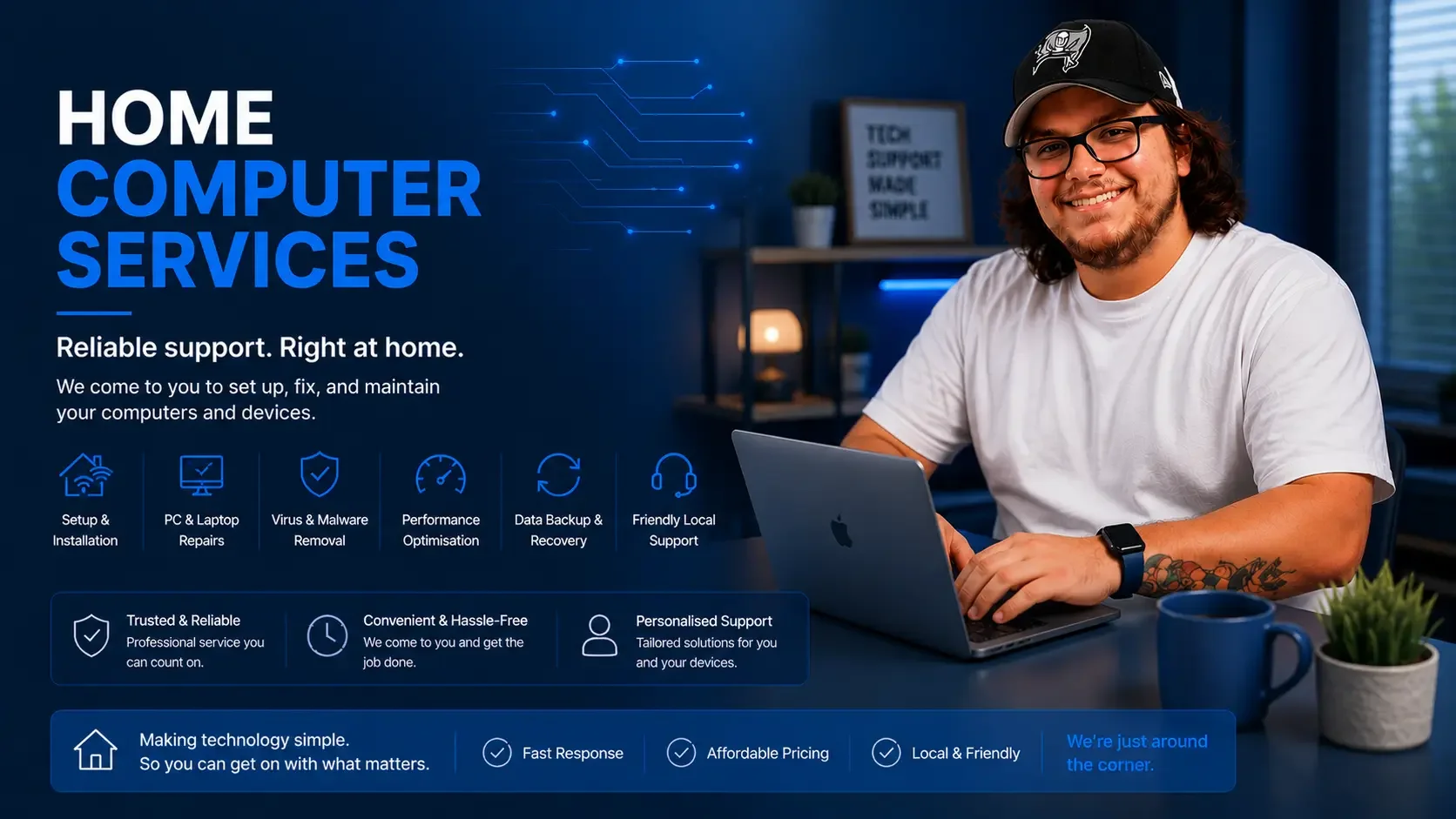 A man with long hair, glasses, and tattoos on his arm sitting at a desk with a laptop, smiling at the camera. The desk has a blue mug and a small plant. Behind him is a room with blue-lit shelves and a window with curtains.