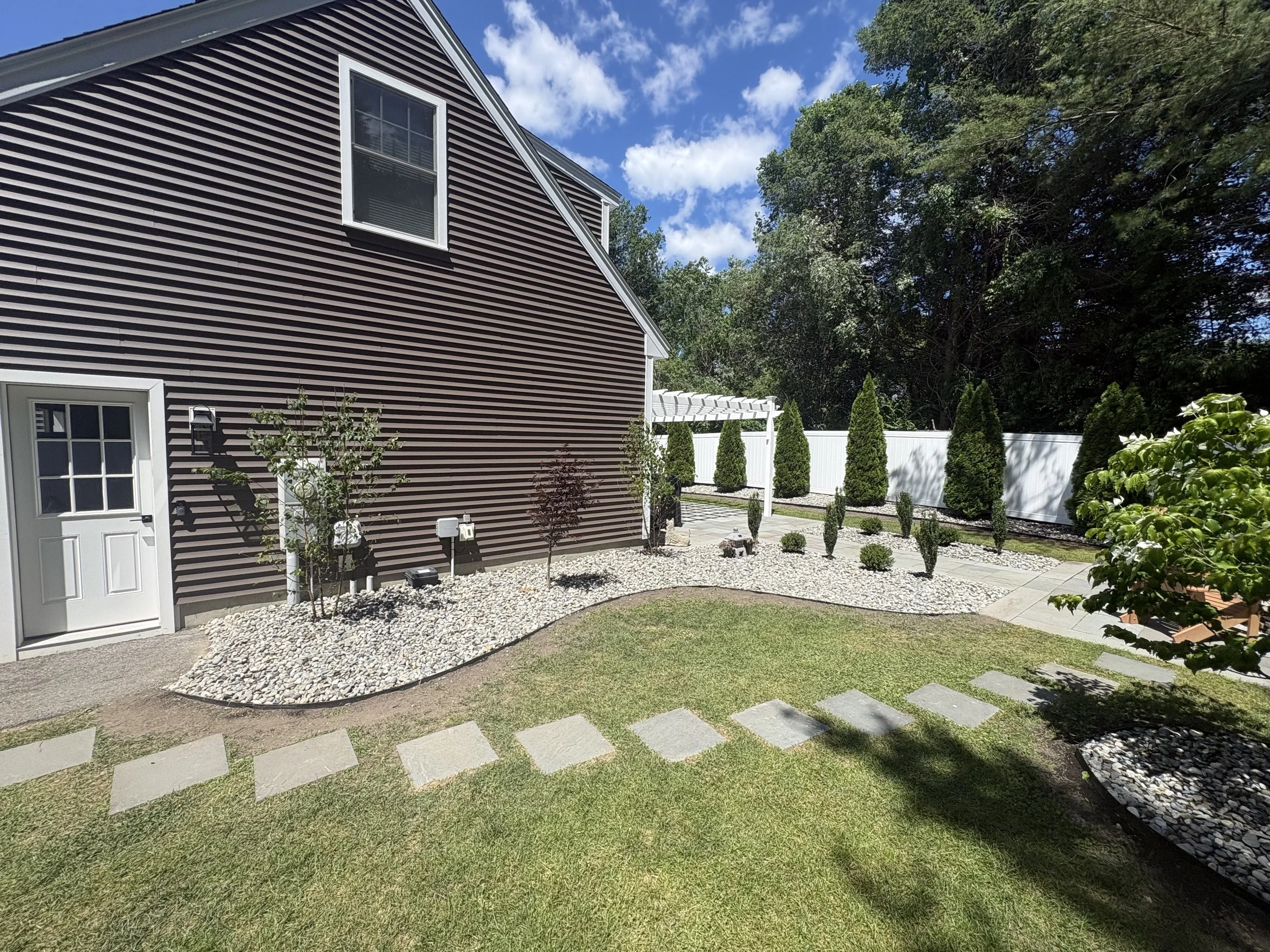 Completed landscape renovation featuring steel edging, plantings, and decorative stone in Greenland, NH.