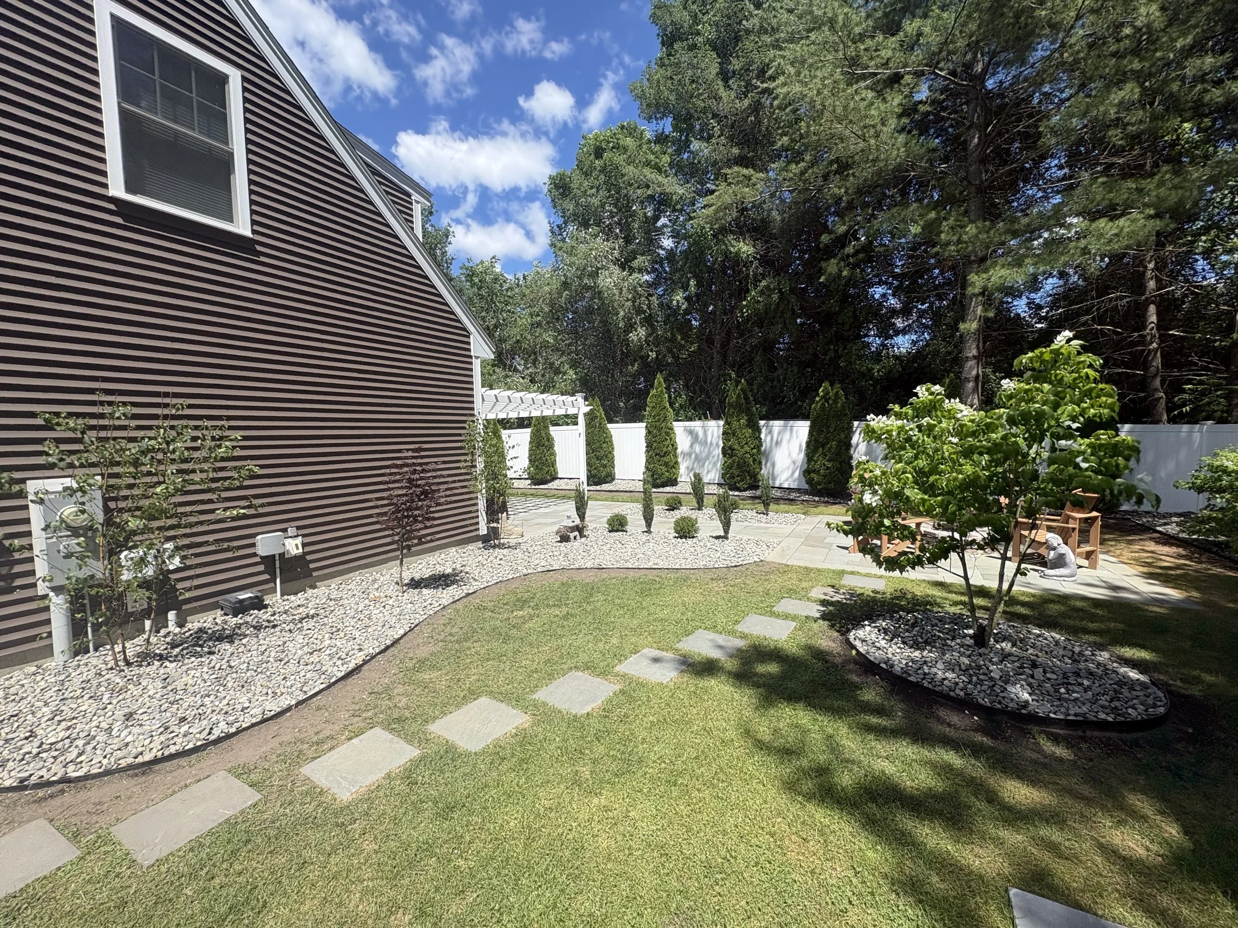 Completed landscape renovation featuring steel edging, plantings, and decorative stone in Greenland, NH.