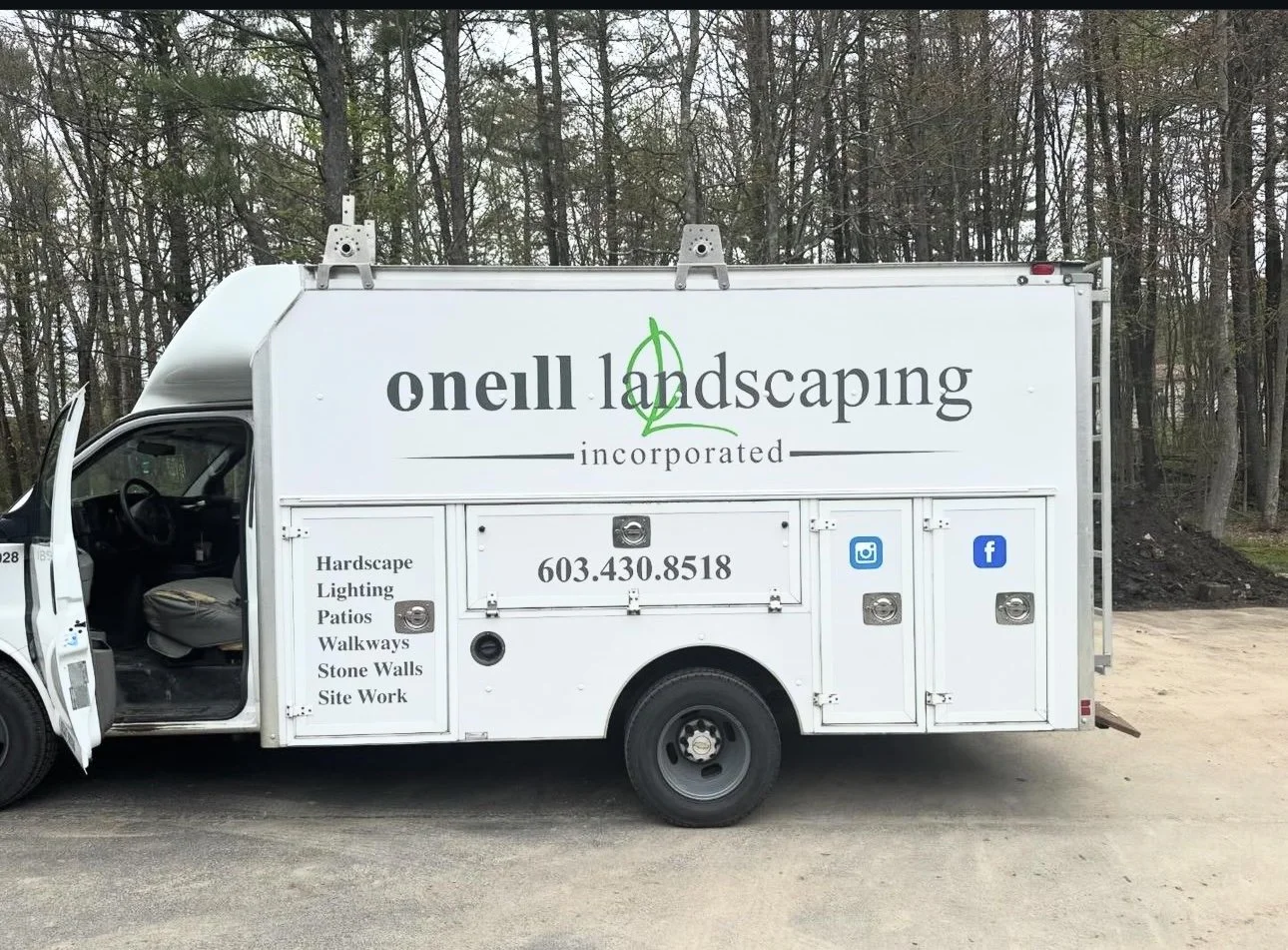 White landscaping service truck with company name 'O'Neill Landscaping' and contact information, parked outdoors near trees.