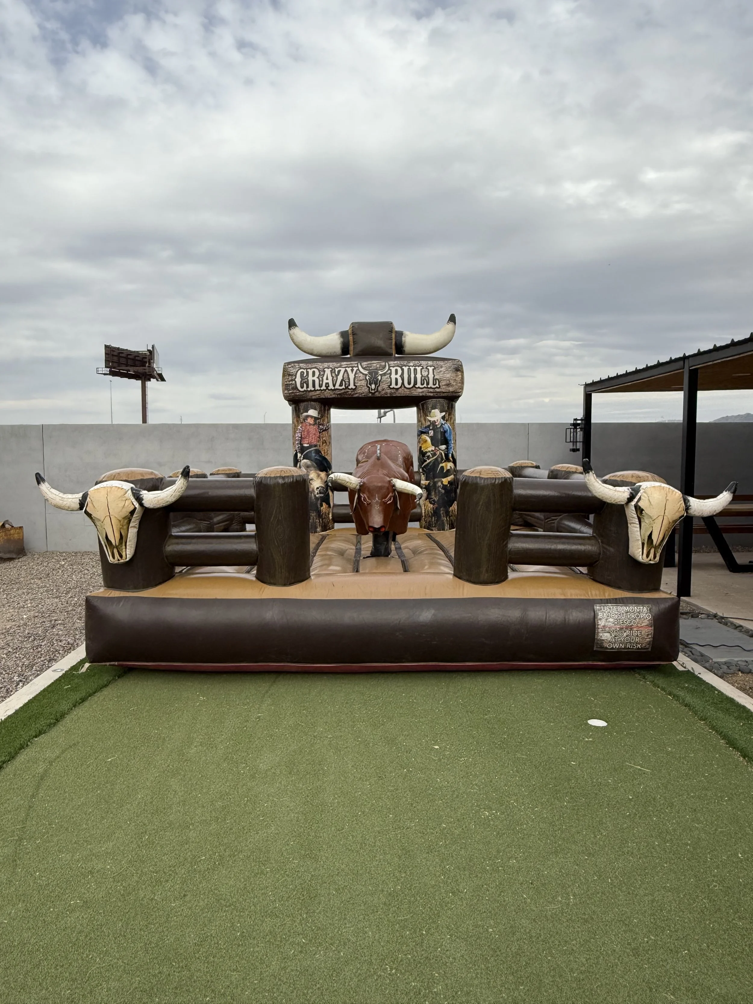 Outdoor mini golf putting green with a large inflatable fake bull and a rodeo-themed obstacle with a sign that says "Crazy Bull."