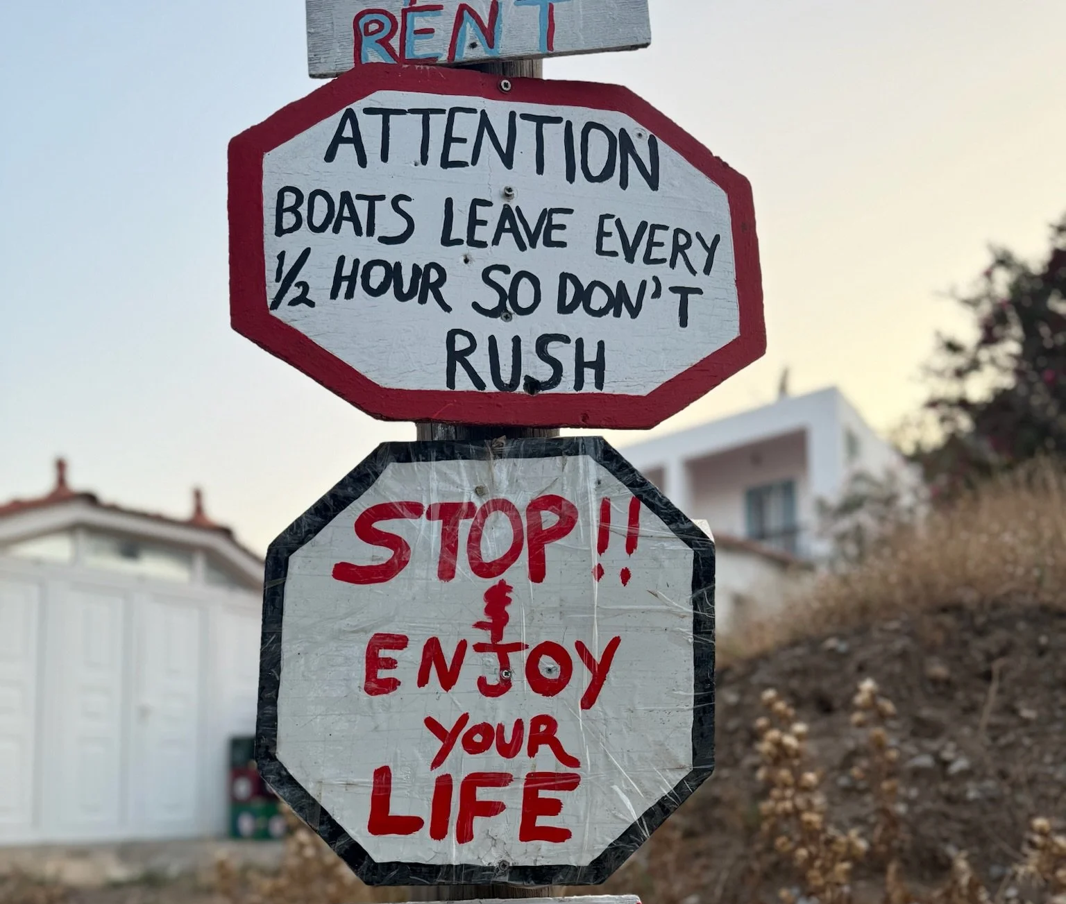Handmade signs on a post with a message to stop and enjoy life.