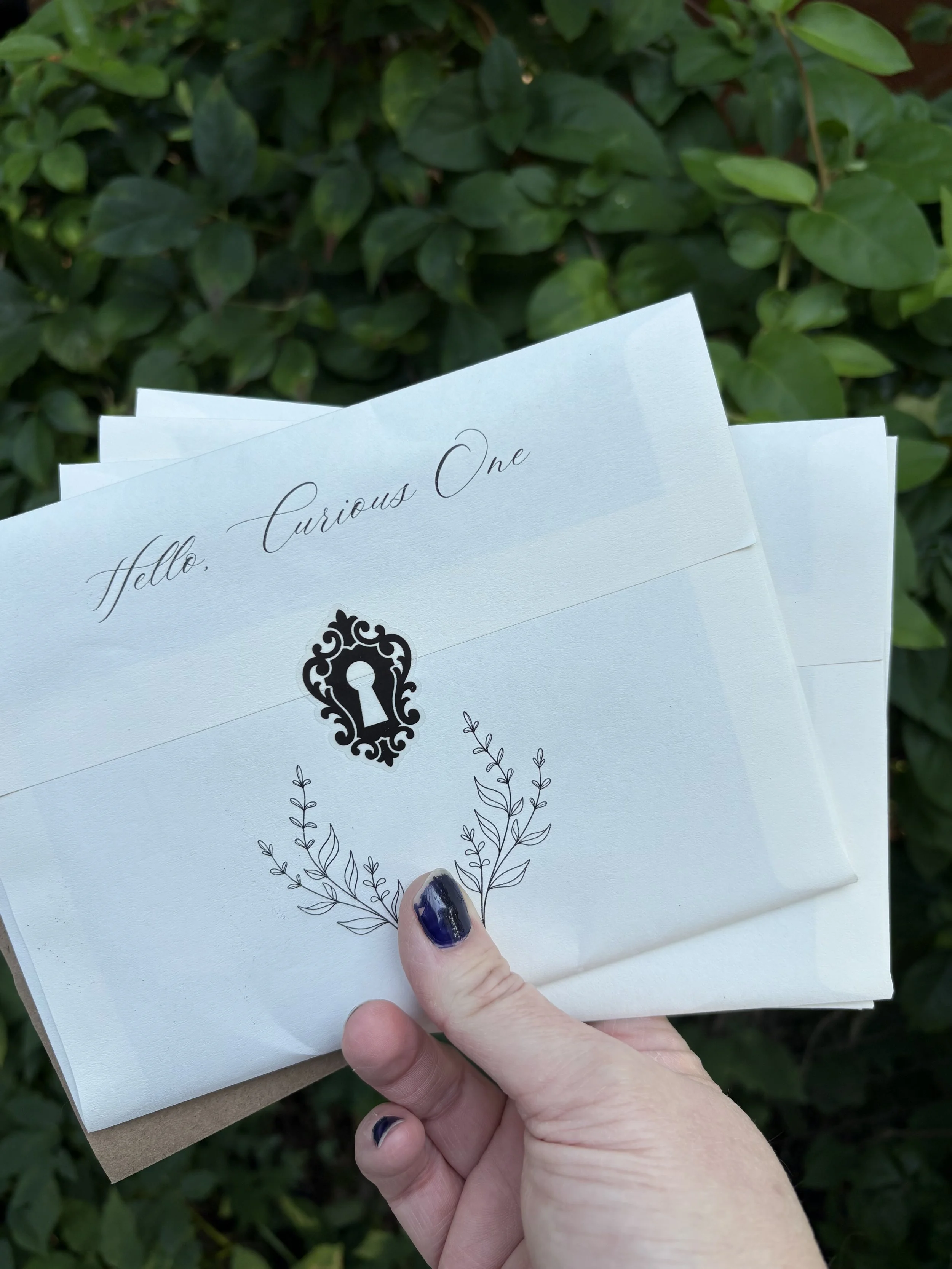 letters held in a hand with a green bush in the background