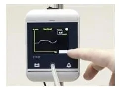 Close-up of a medical monitor displaying a graph, with a hand using a touchscreen interface.