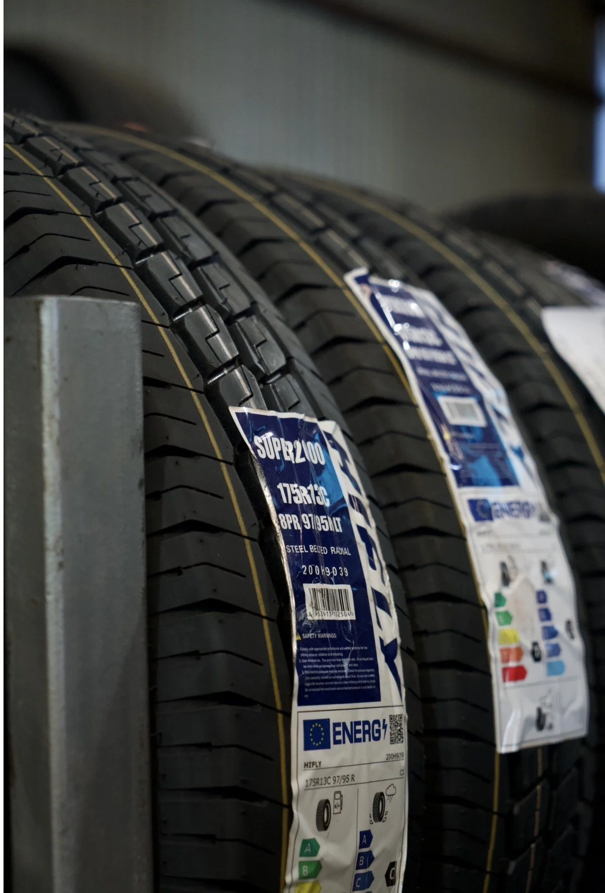 Close-up of new black tires with yellow lines, stacked on a shelf, with labels showing specifications and energy ratings.