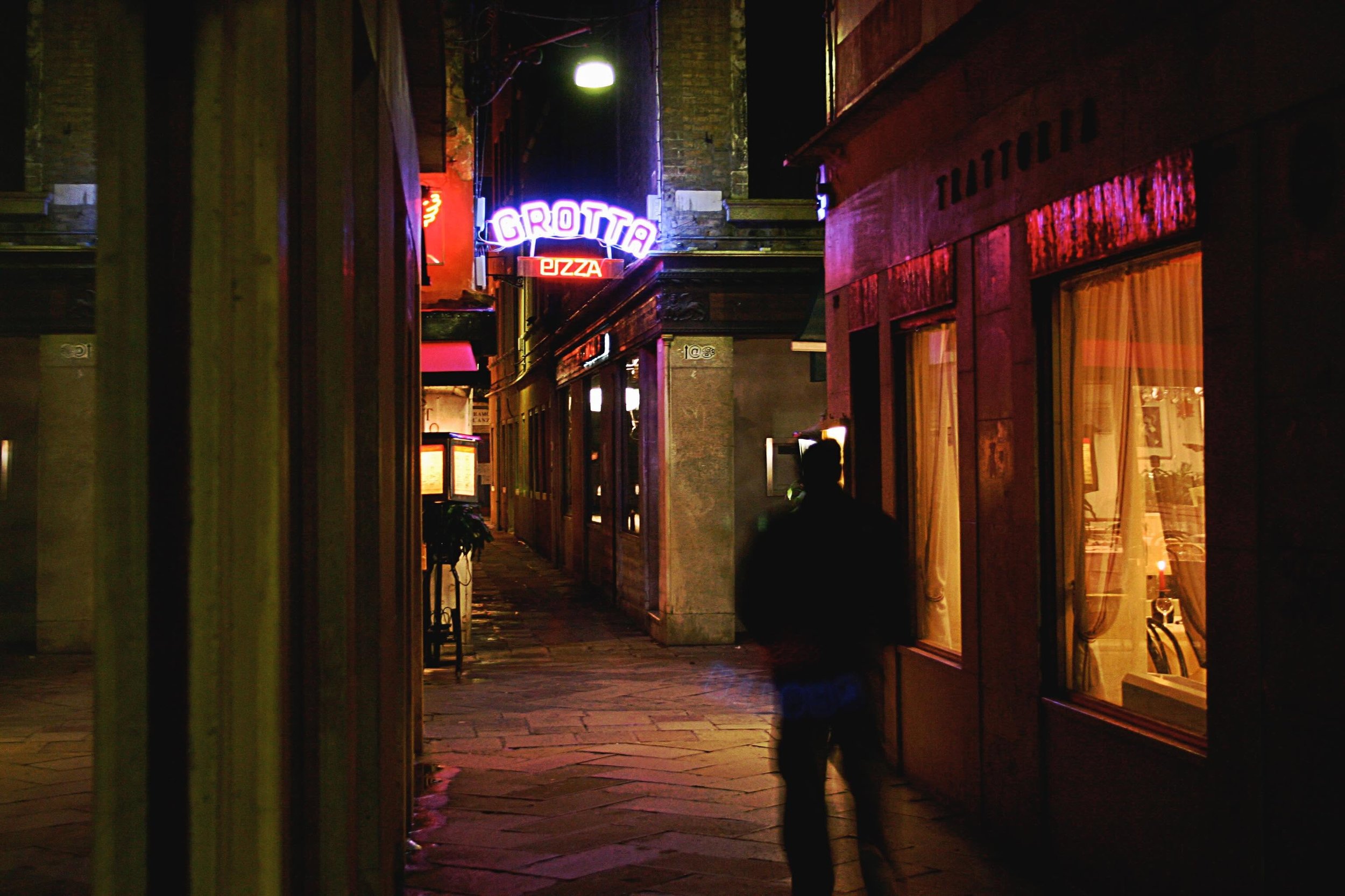 A man walks the lonely, neon-lit alleys of Venice, Italy