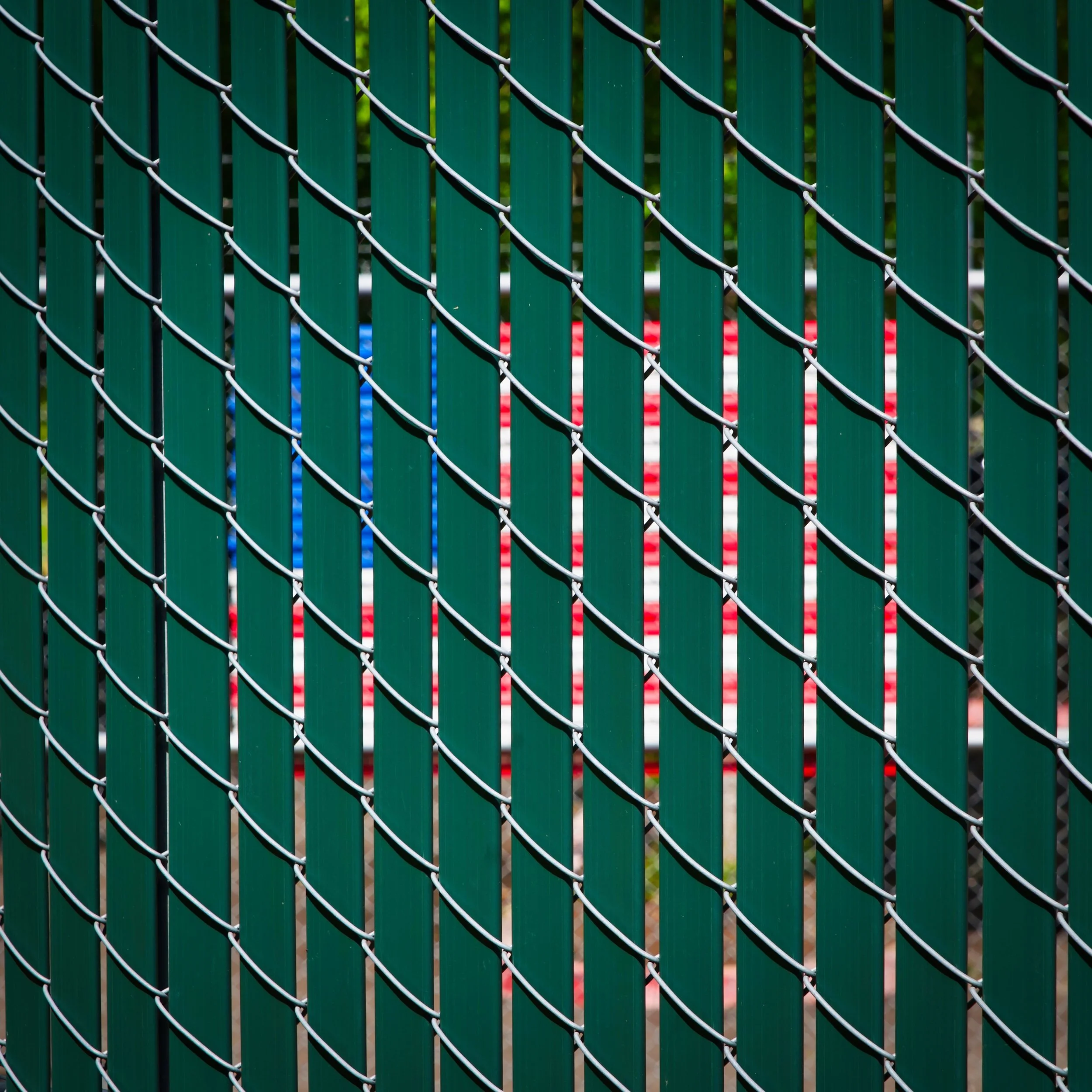 US Flag peeks from behind a chainlink fence with green slats - Wilsonville, Oregon