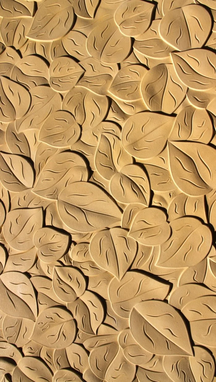 Close-up of beige embossed leaves arranged closely together, creating a textured pattern.