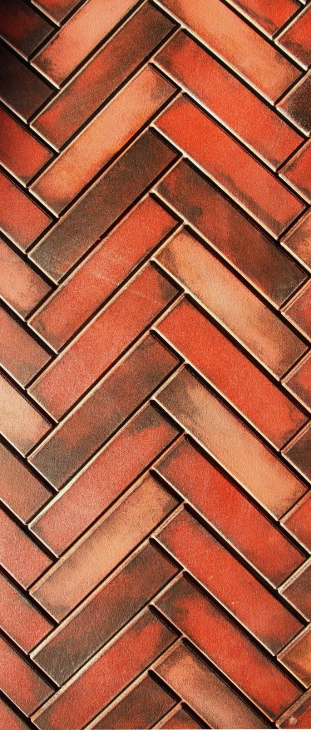 Close-up view of a brick wall with bricks arranged in a herringbone pattern.